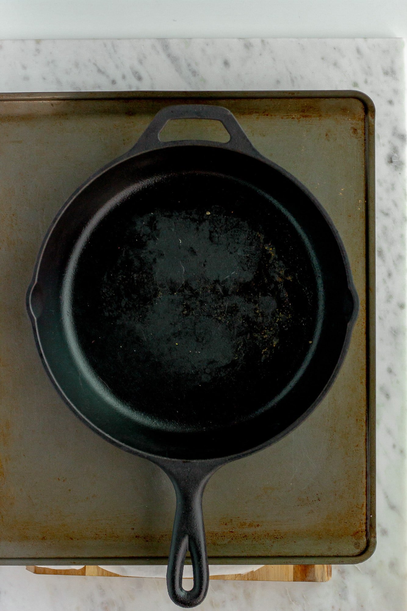 a black skillet placed on top of a baking sheet.