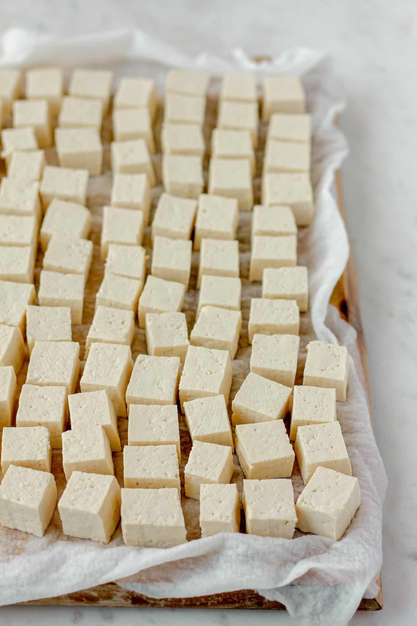 rows of tofu cubes on a paper towel-lined cutting board.