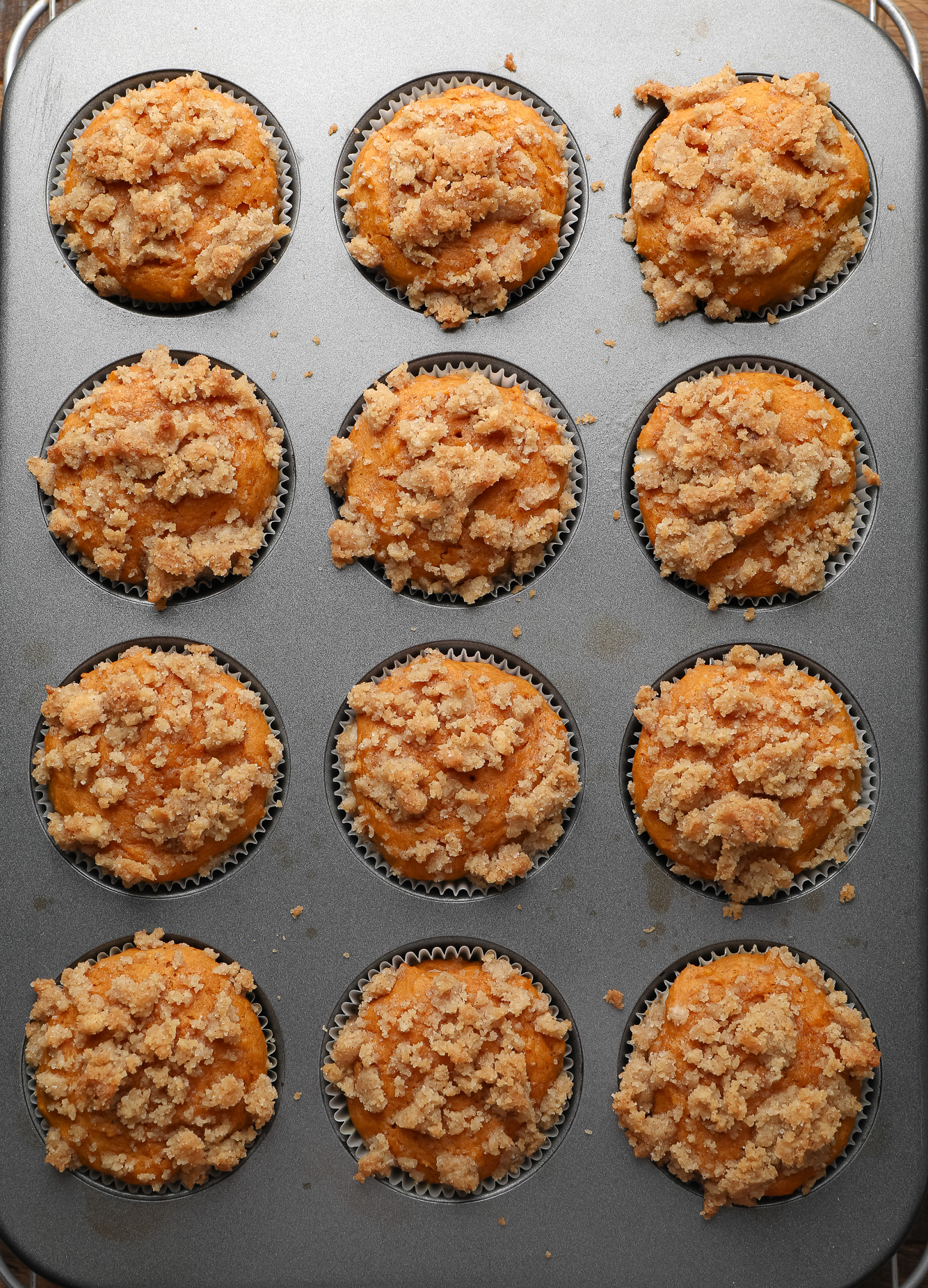 baked vegan pumpkin cream cheese muffins topped with cinnamon streusel in a muffin tin.