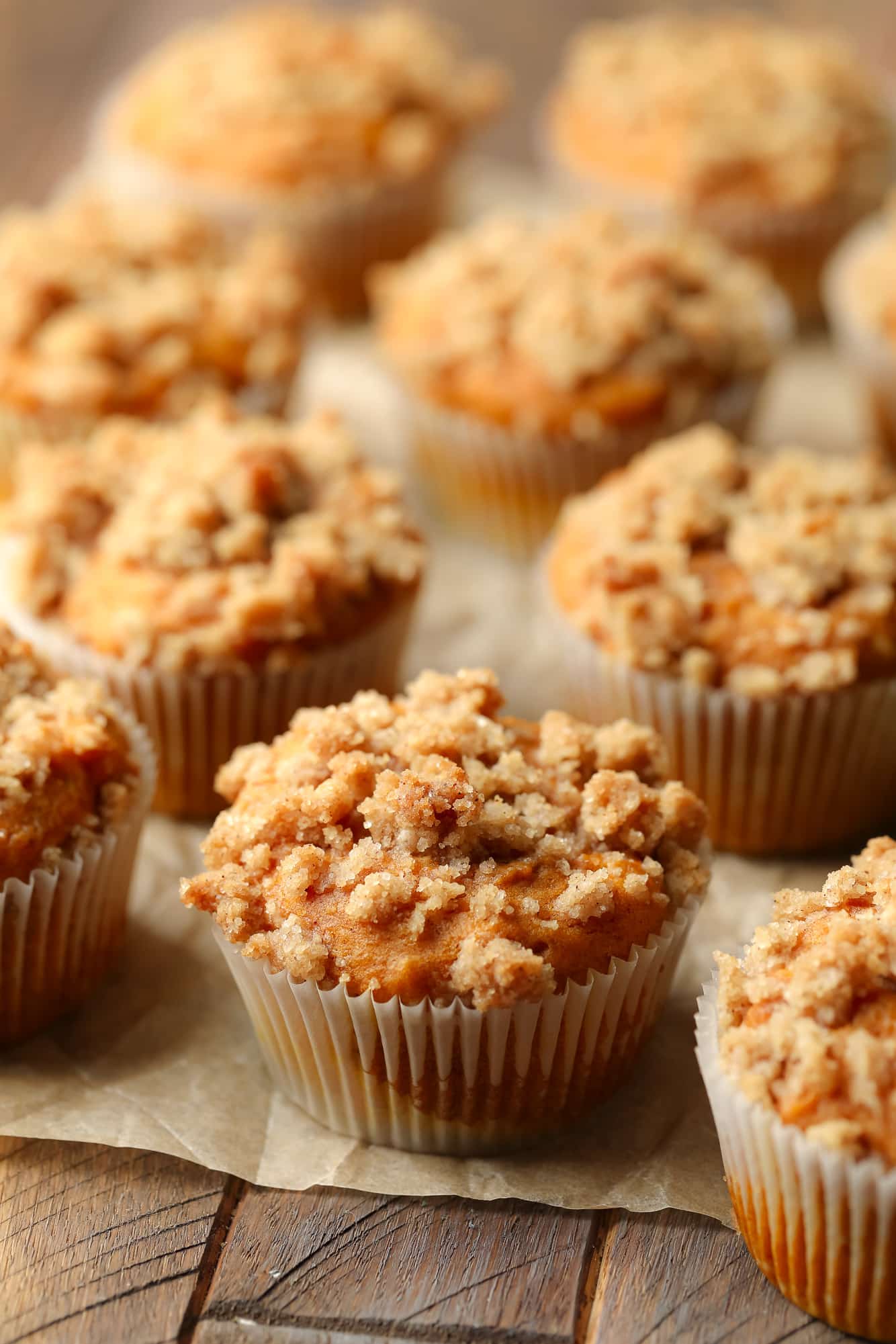 rows of baked vegan pumpkin cream cheese muffins on a piece of parchment paper.