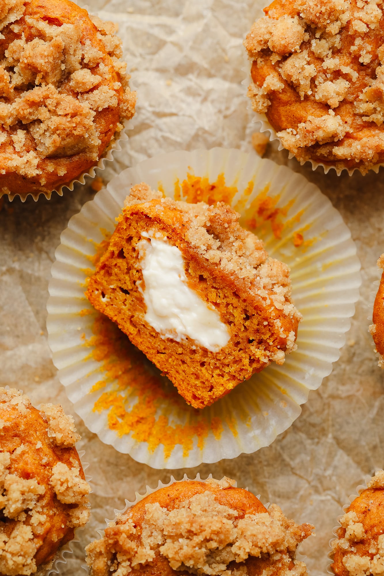 a vegan pumpkin cream cheese muffin sliced in half and turned on its side, showing vegan cream cheese in the middle.