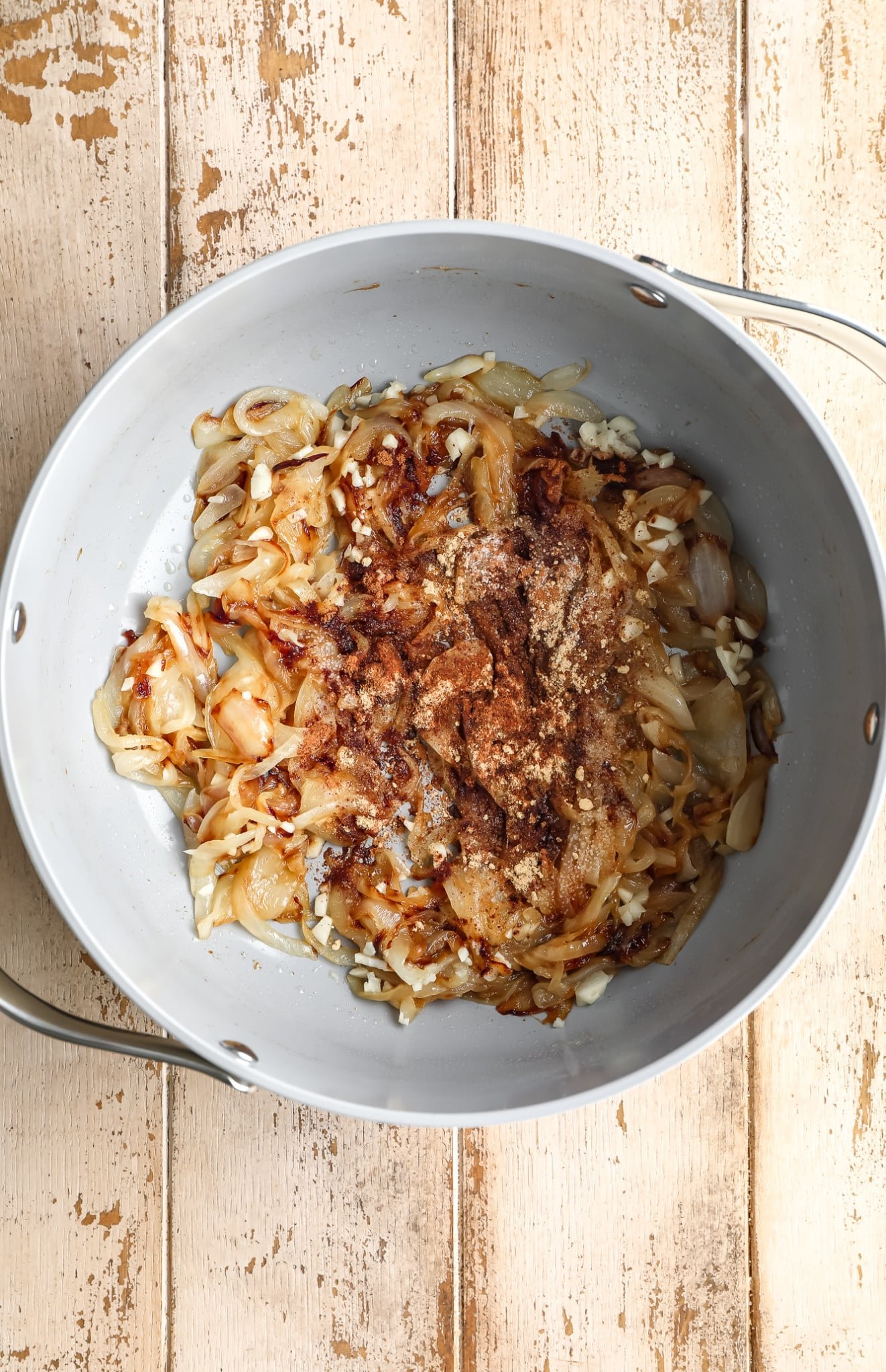 caramelized onions covered with spices in a grey pot.