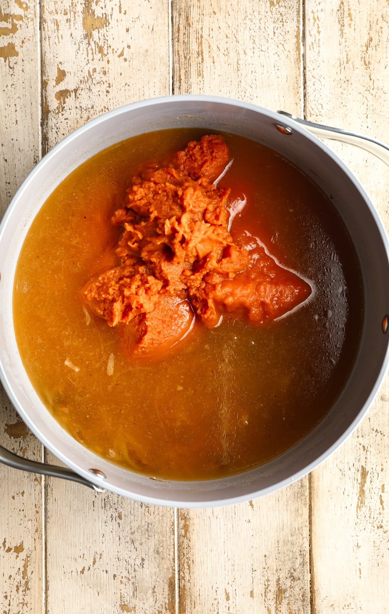 ingredients for vegan pumpkin soup in a large grey pot.