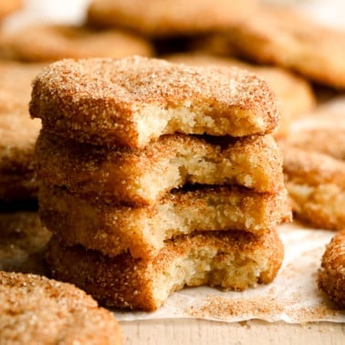 a stack of 4 vegan snickerdoodles with bites taken out of each of them.