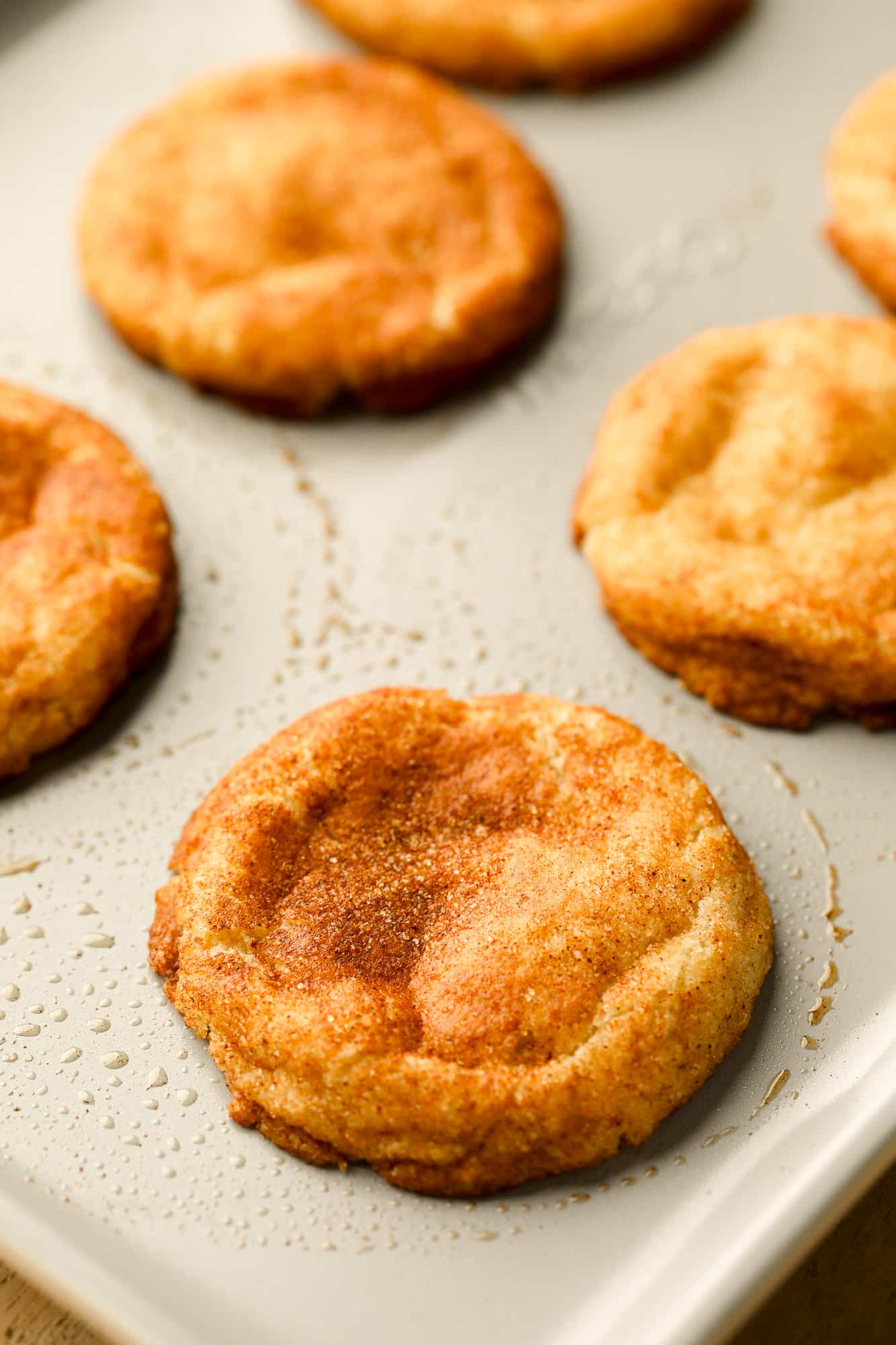 close up on baked vegan snickerdoodles in rows on a metal baking sheet.