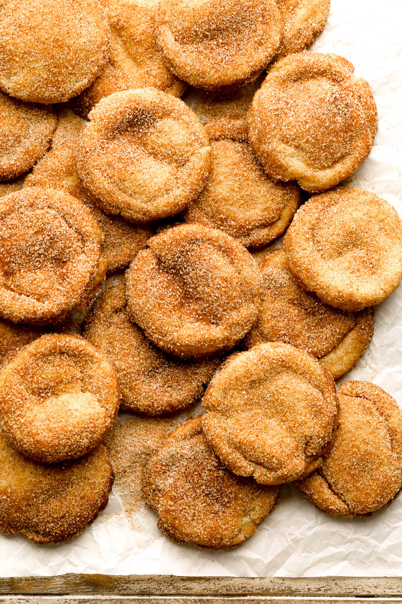 a pile of vegan snickerdoodles on a piece of parchment paper.