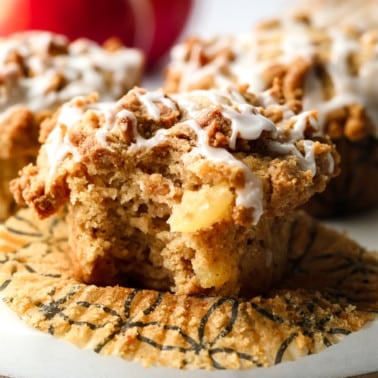 apple muffin on a white board with a bite taken out of it with glaze