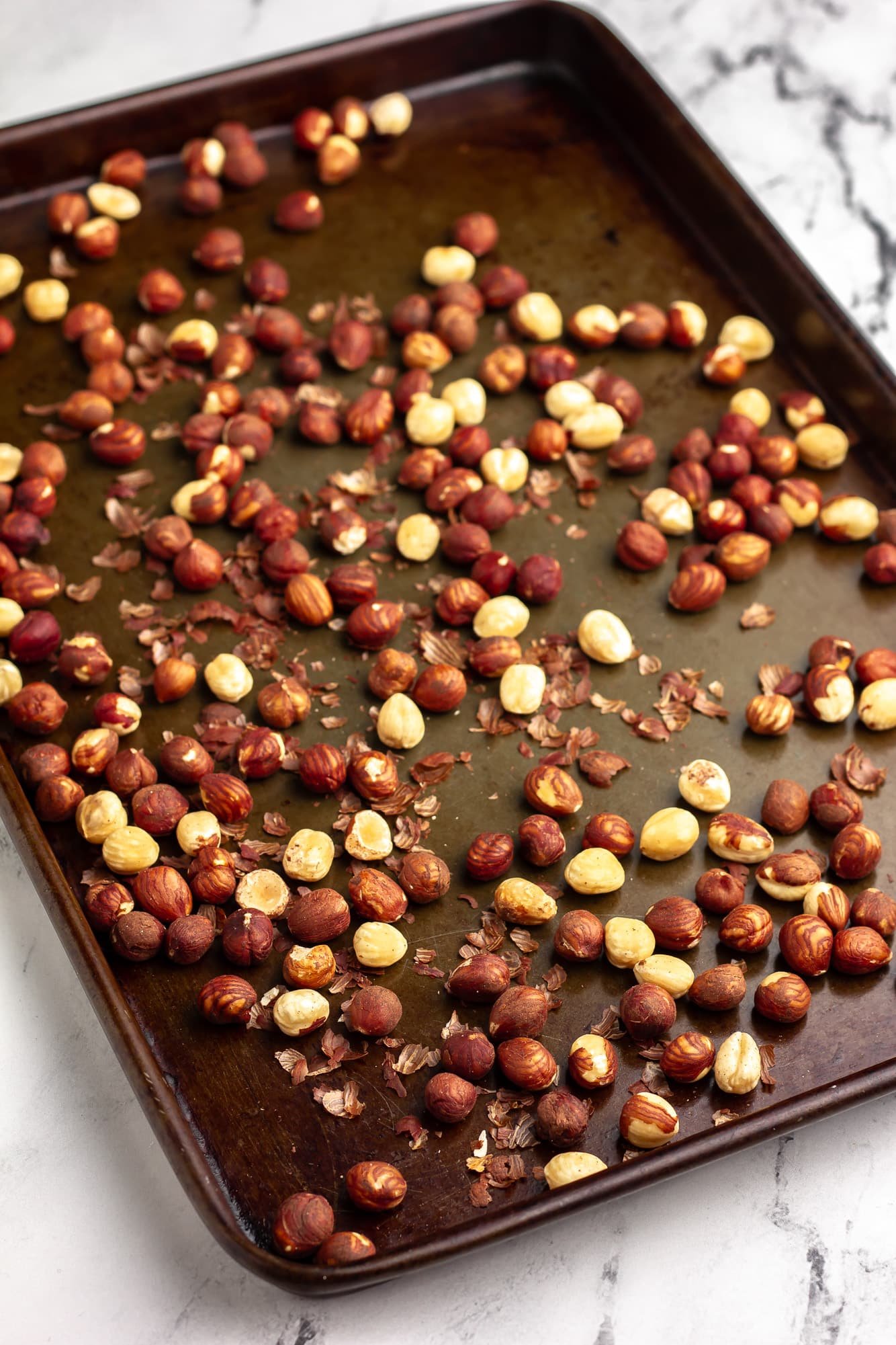 roasted hazelnuts on a metal baking sheet.