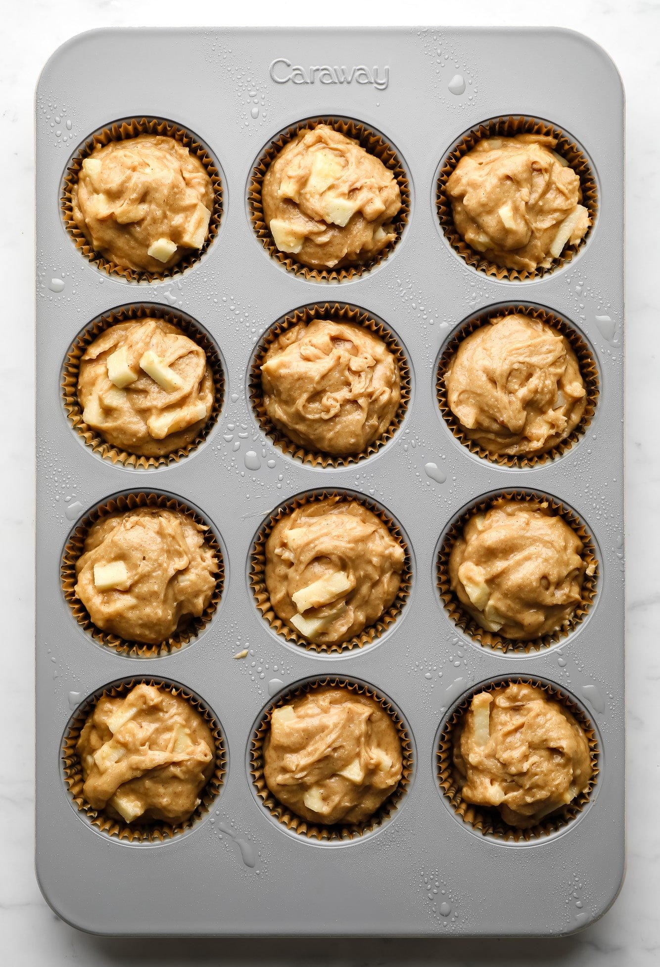 unbaked vegan apple muffin batter in a muffin tin.