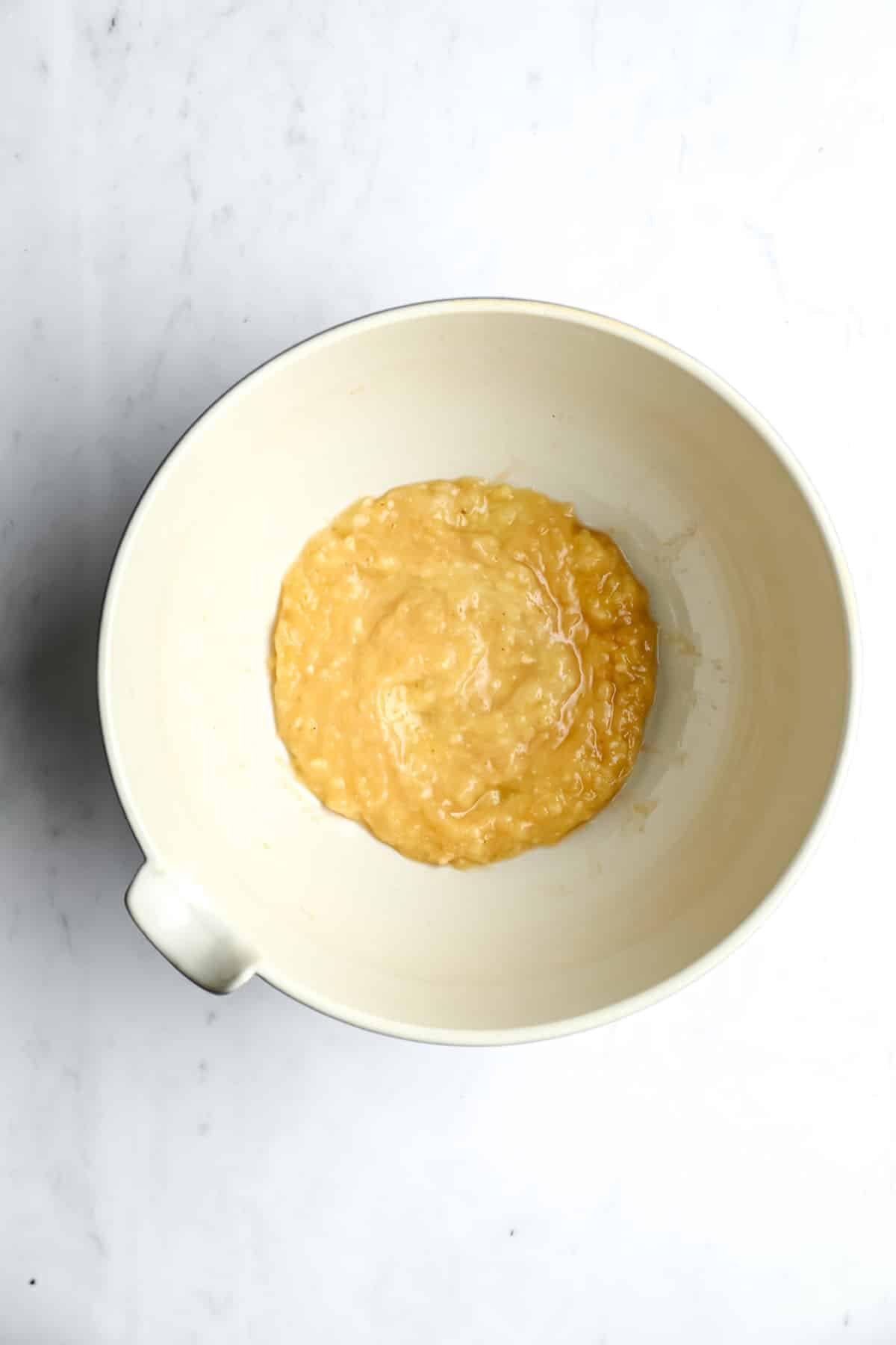 mashed bananas in a bowl on white backdrop