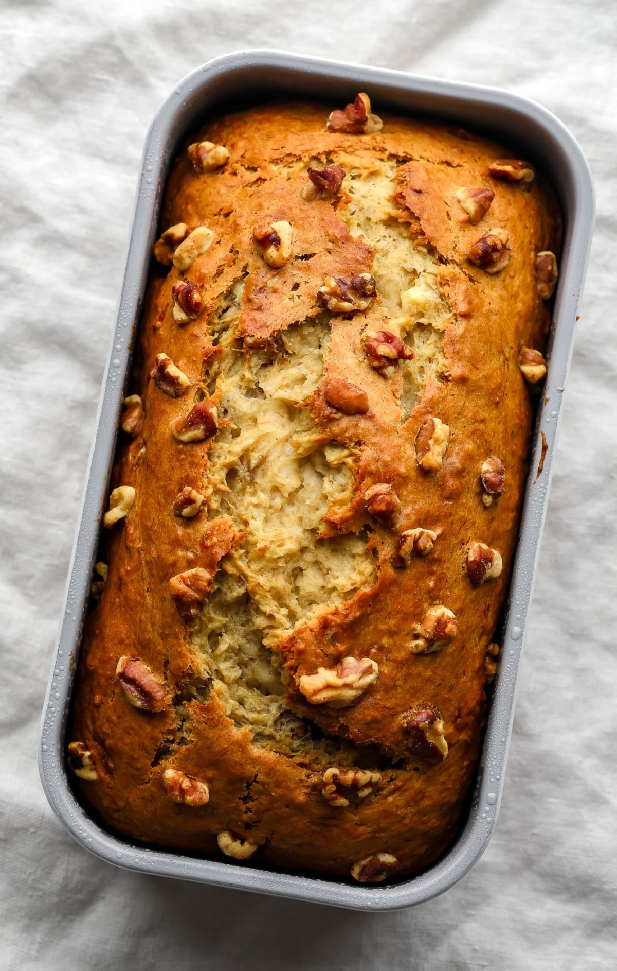 whole cooked banana bread with walnuts on light grey towel