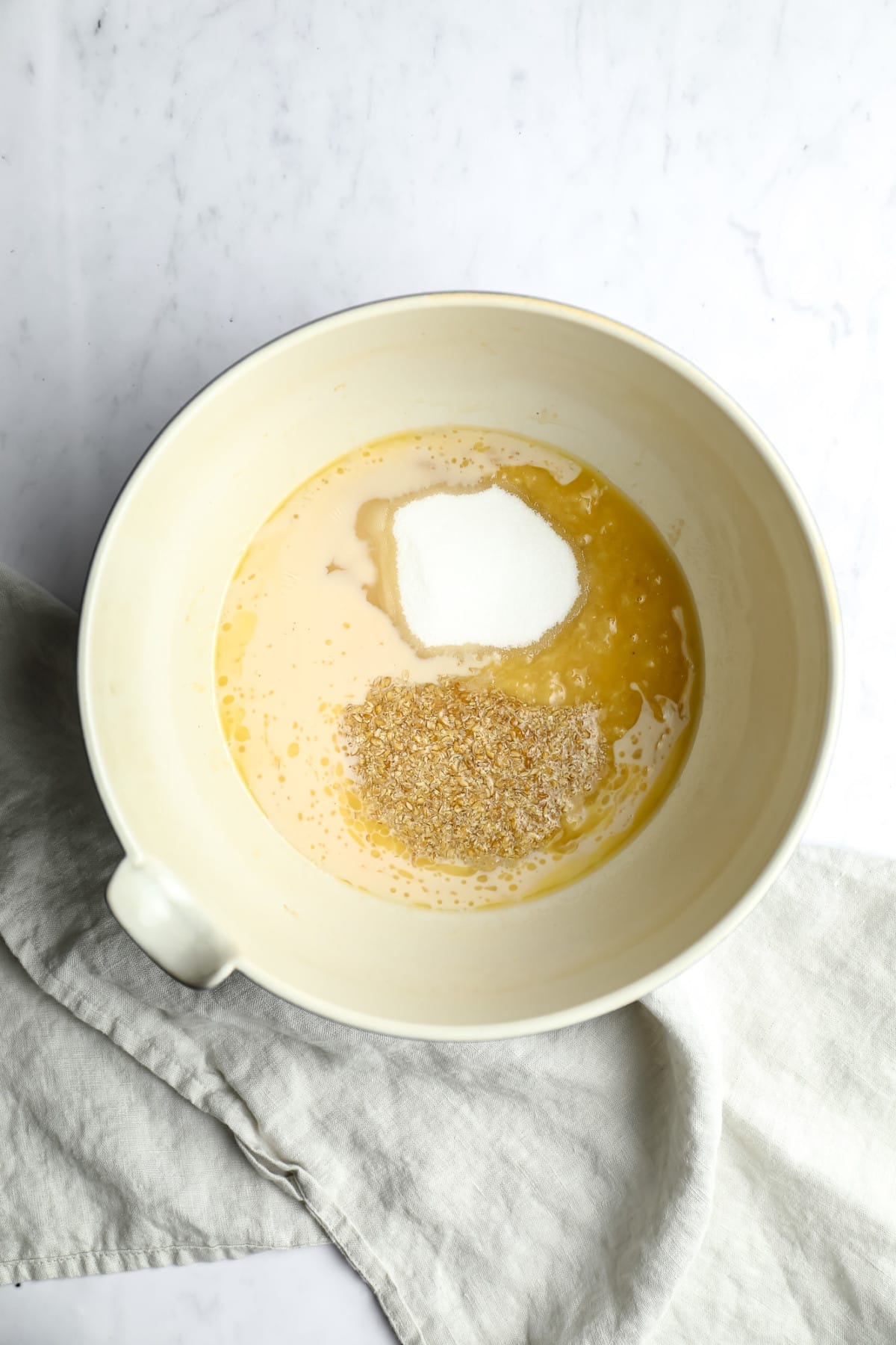 bowl with flaxseeds, sugar and milk/butter on white marble backdrop