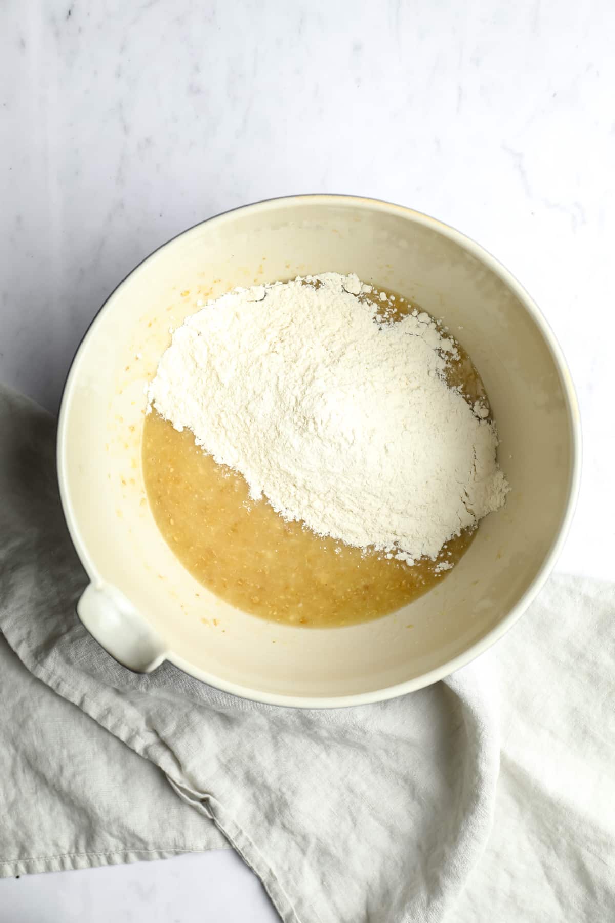 yellow mixture with flour on top in a bowl on white background