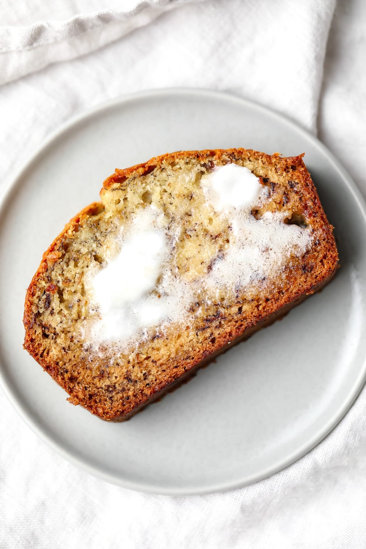 slice of bread with butter on grey towel