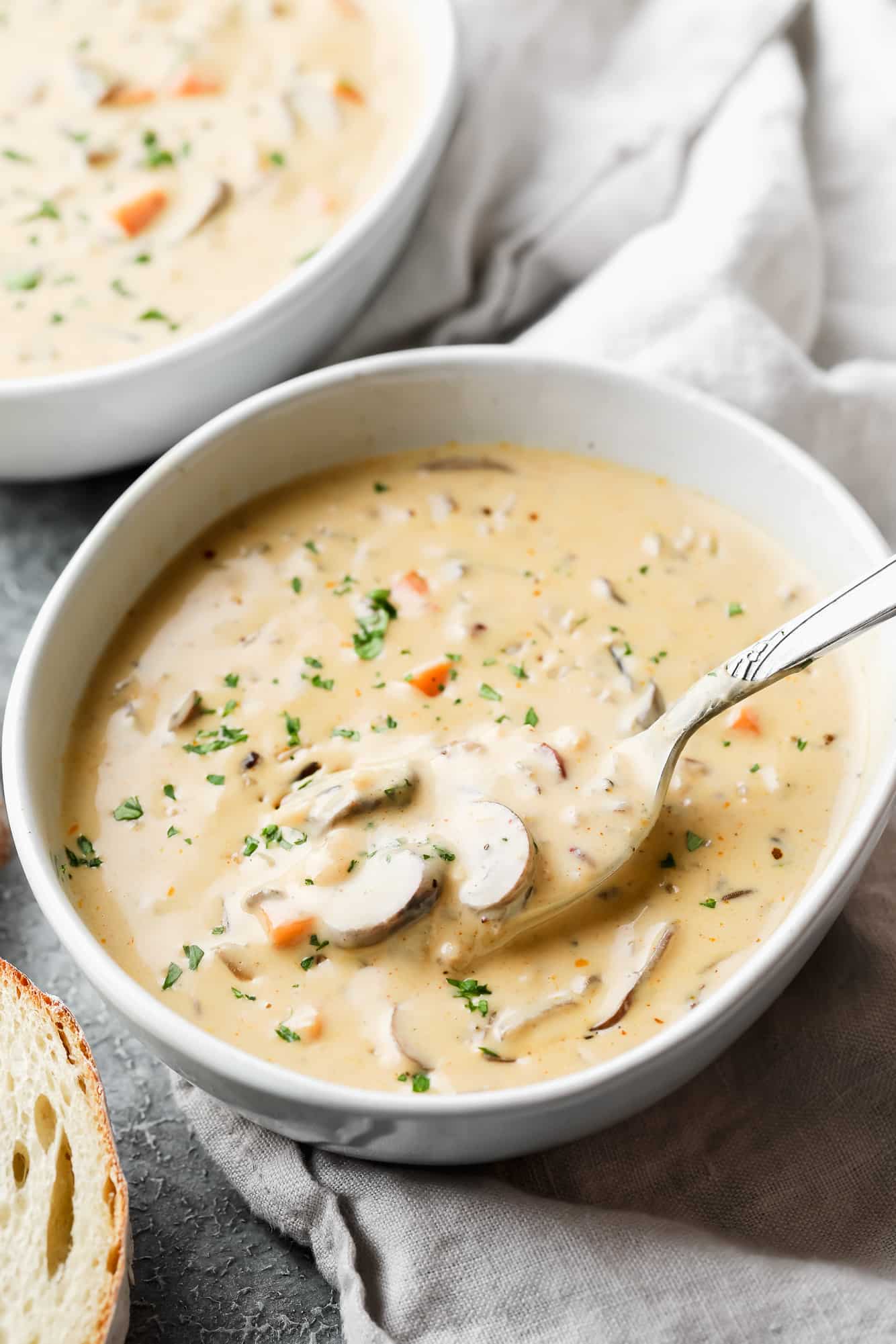 vegan mushroom soup in a white bowl with a metal spoon.