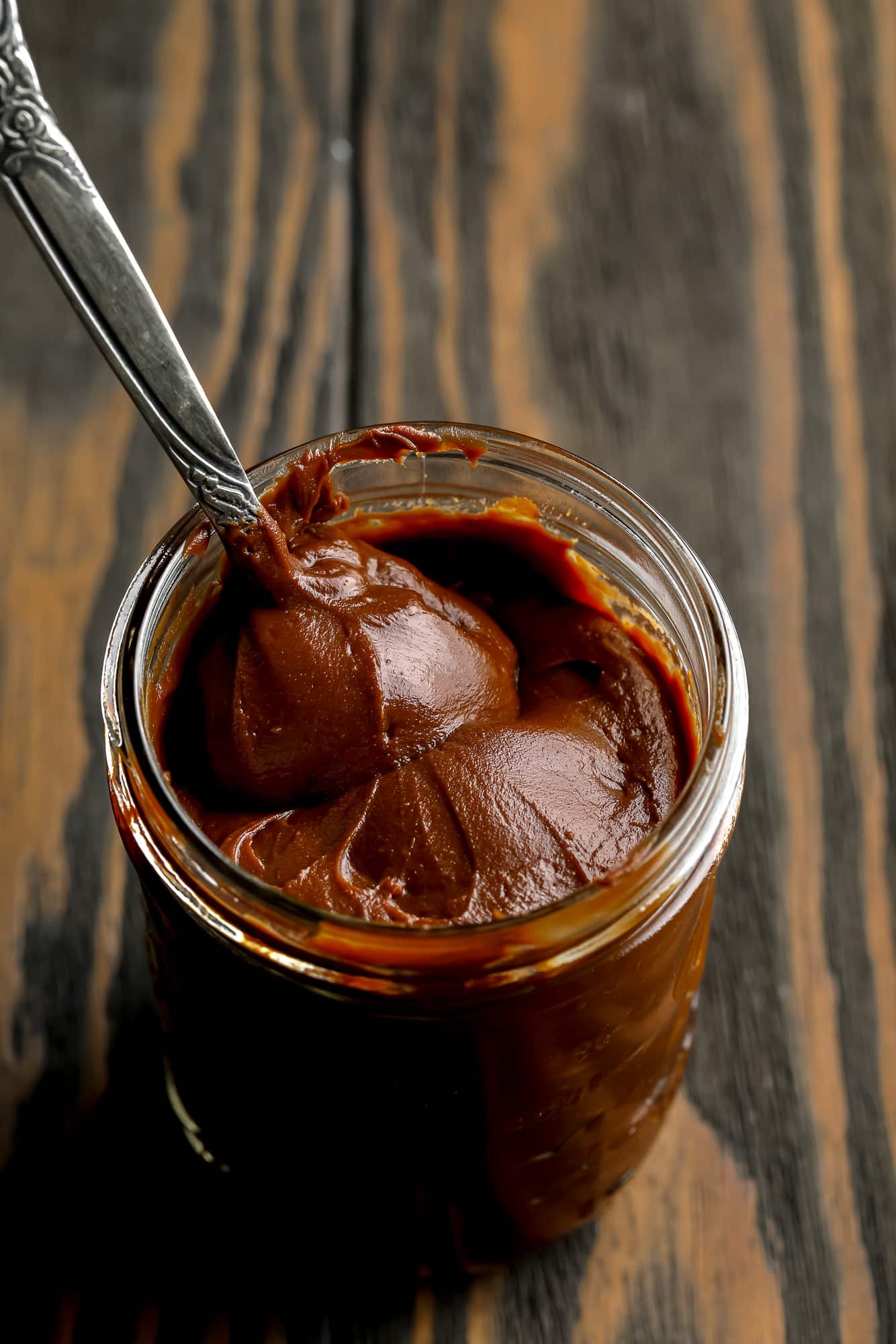 a metal spoon in a glass jar of vegan nutella.