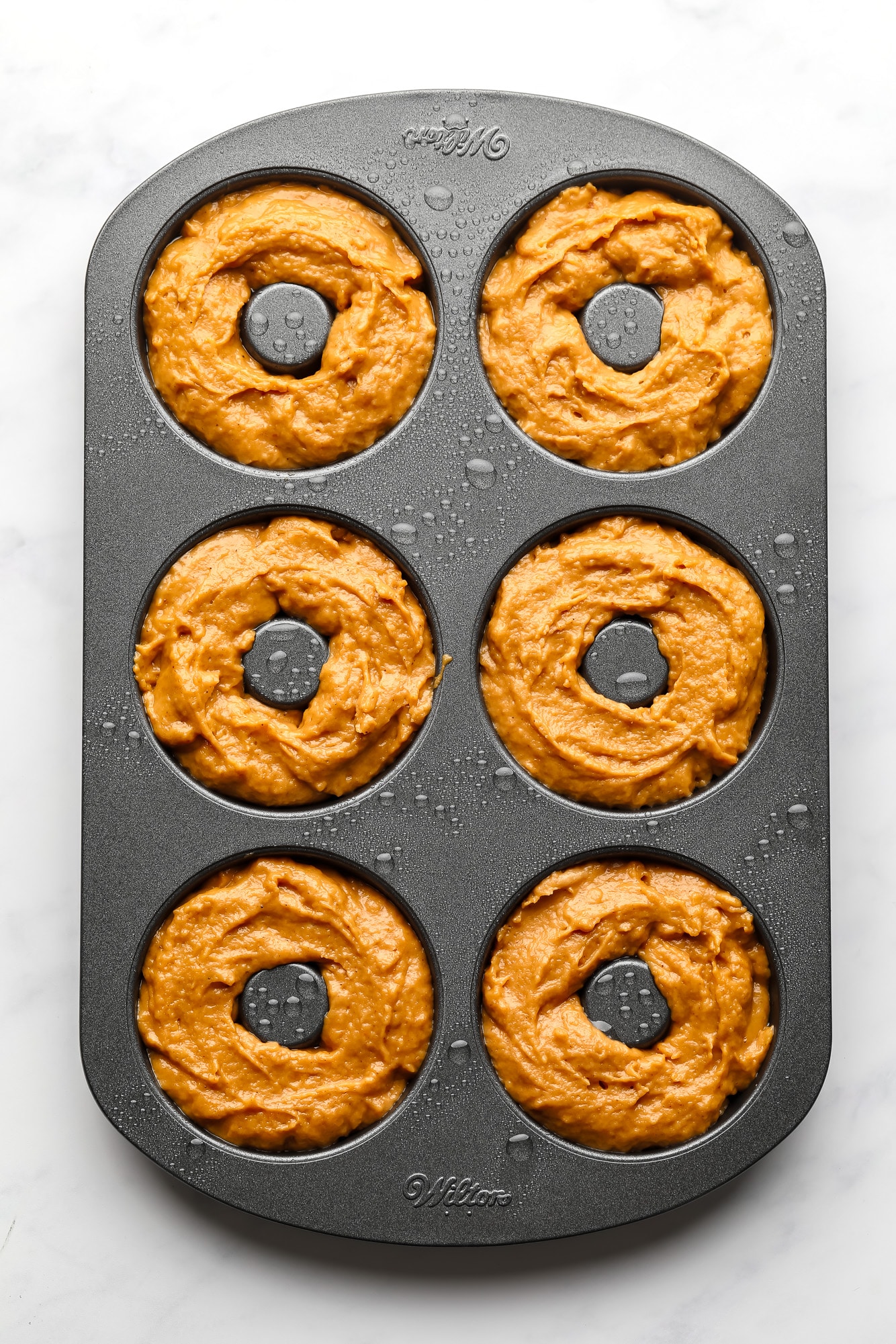 a donut pan filled with vegan pumpkin donut batter.