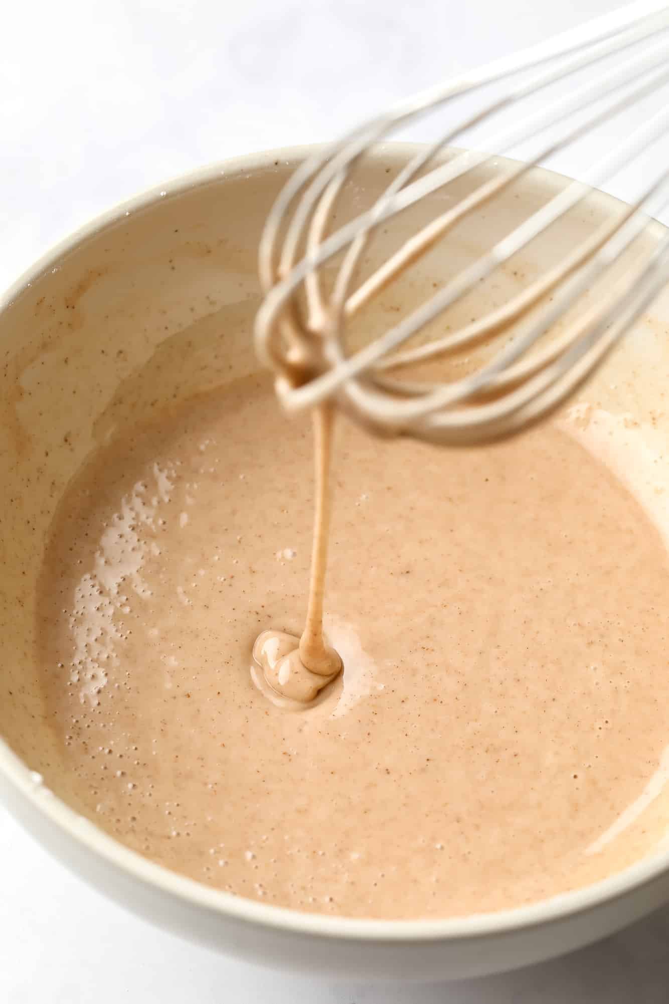 using a whisk to stir vegan pumpkin donut batter.