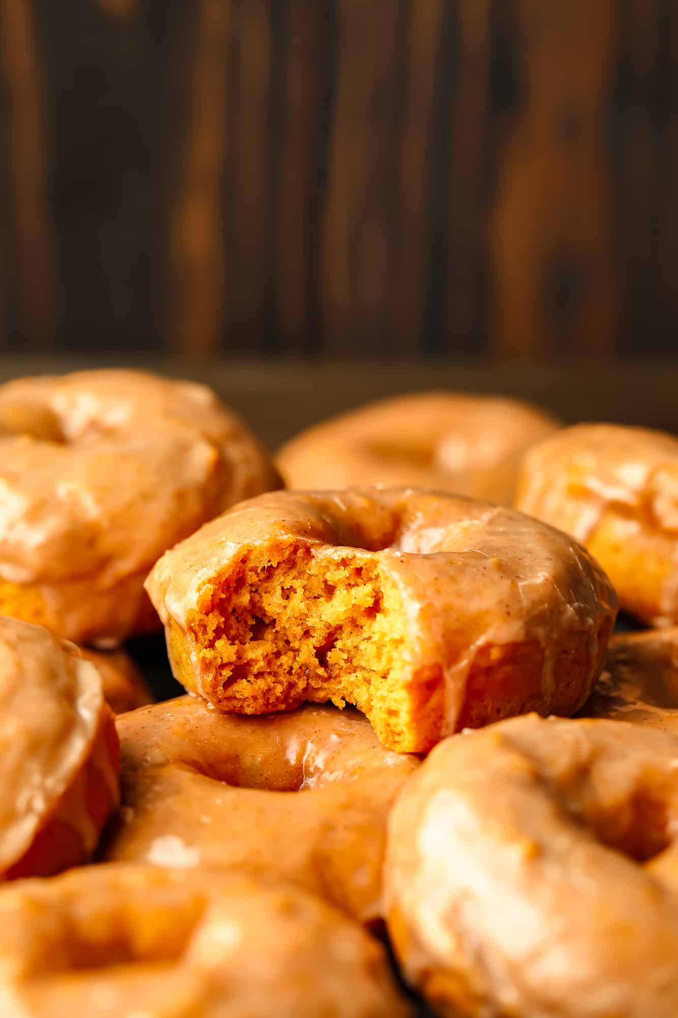 close up on a vegan pumpkin donut with a bite taken out of it.