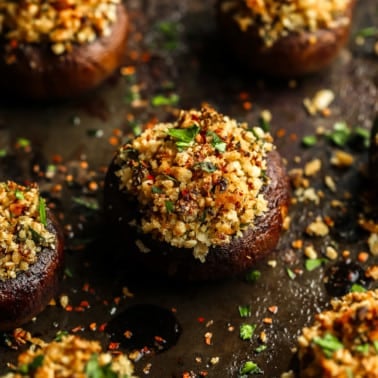 close up on a baked stuffed mushroom with a vegan parmesan and breadcrumb filling.