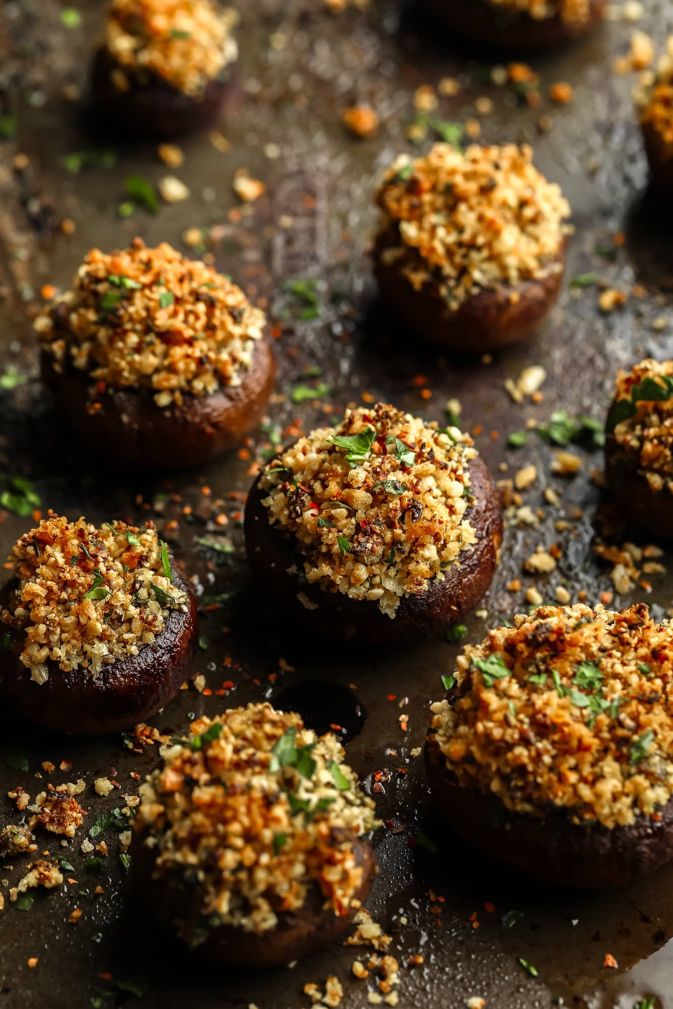 close up on baked stuffed mushrooms with a vegan parmesan and breadcrumb filling.