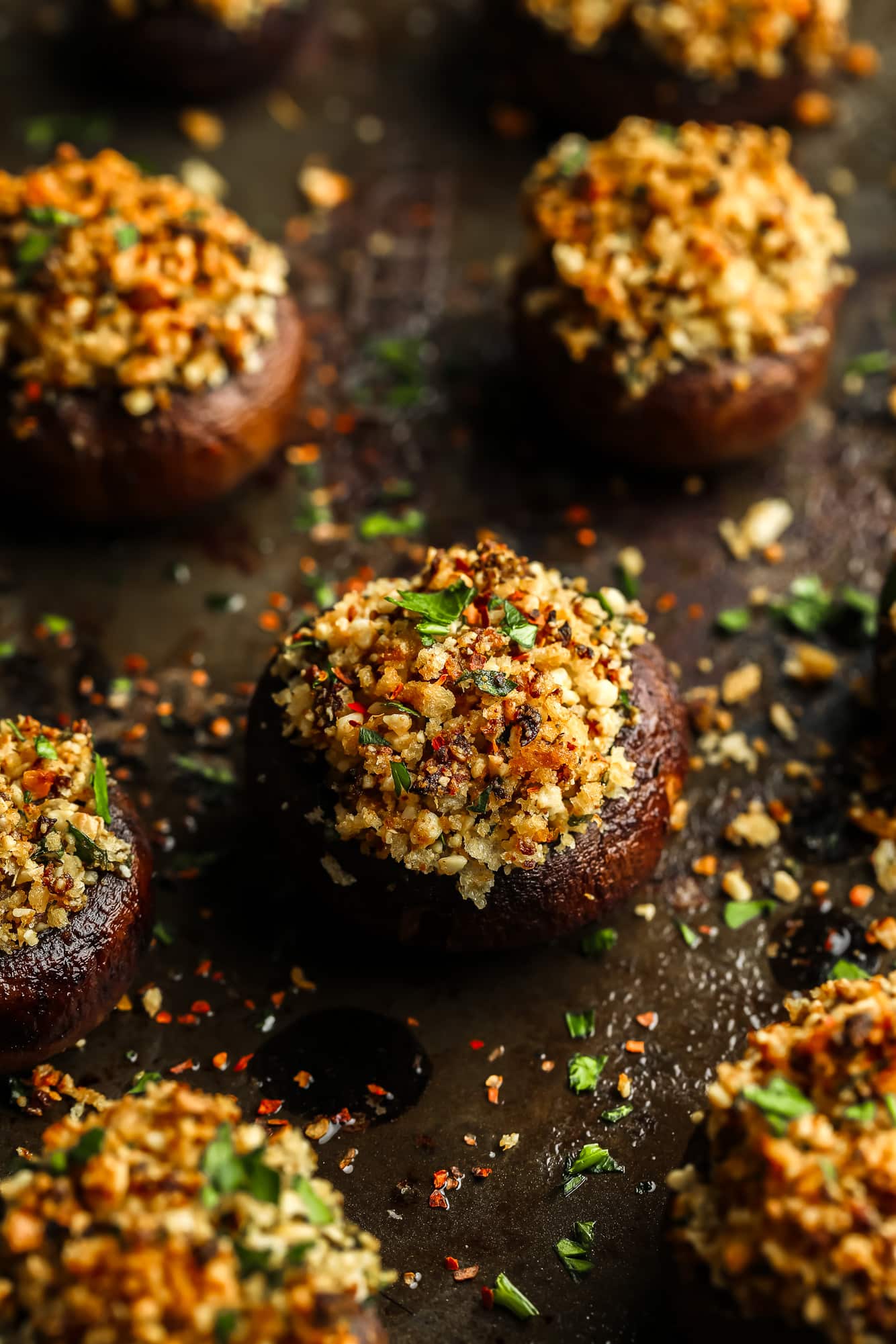 close up on a baked stuffed mushroom with a vegan parmesan and breadcrumb filling.