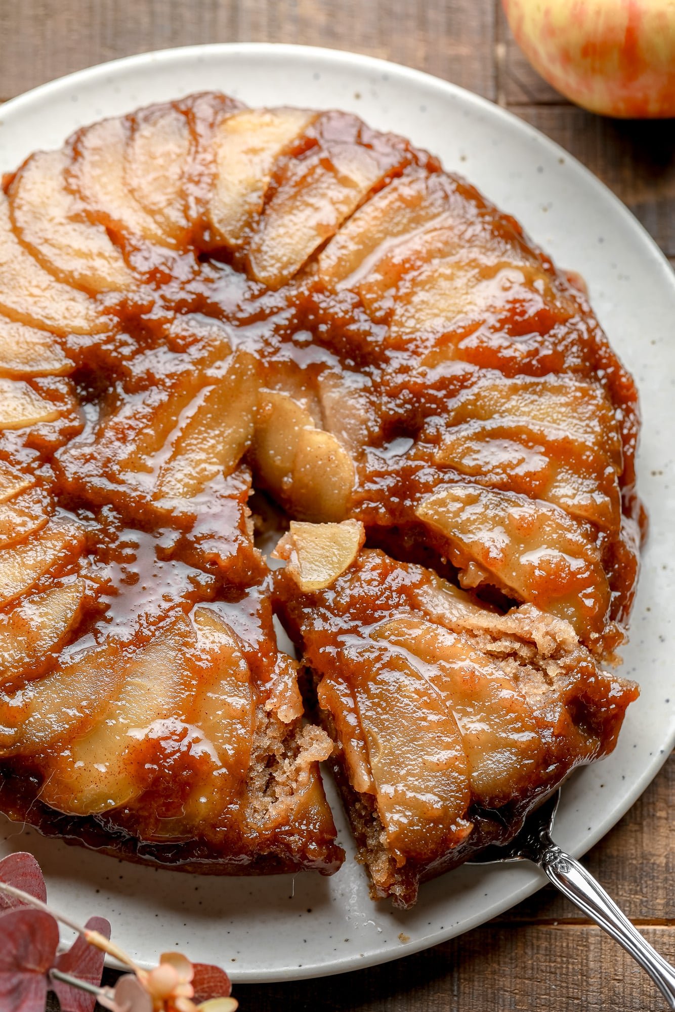 A slice being lifted from an Apple Upside Down Cake on a white plate.