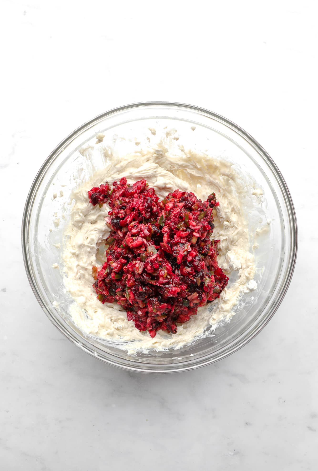 blended cranberries and jalapenos on top of whipped cream cheese in a glass bowl.