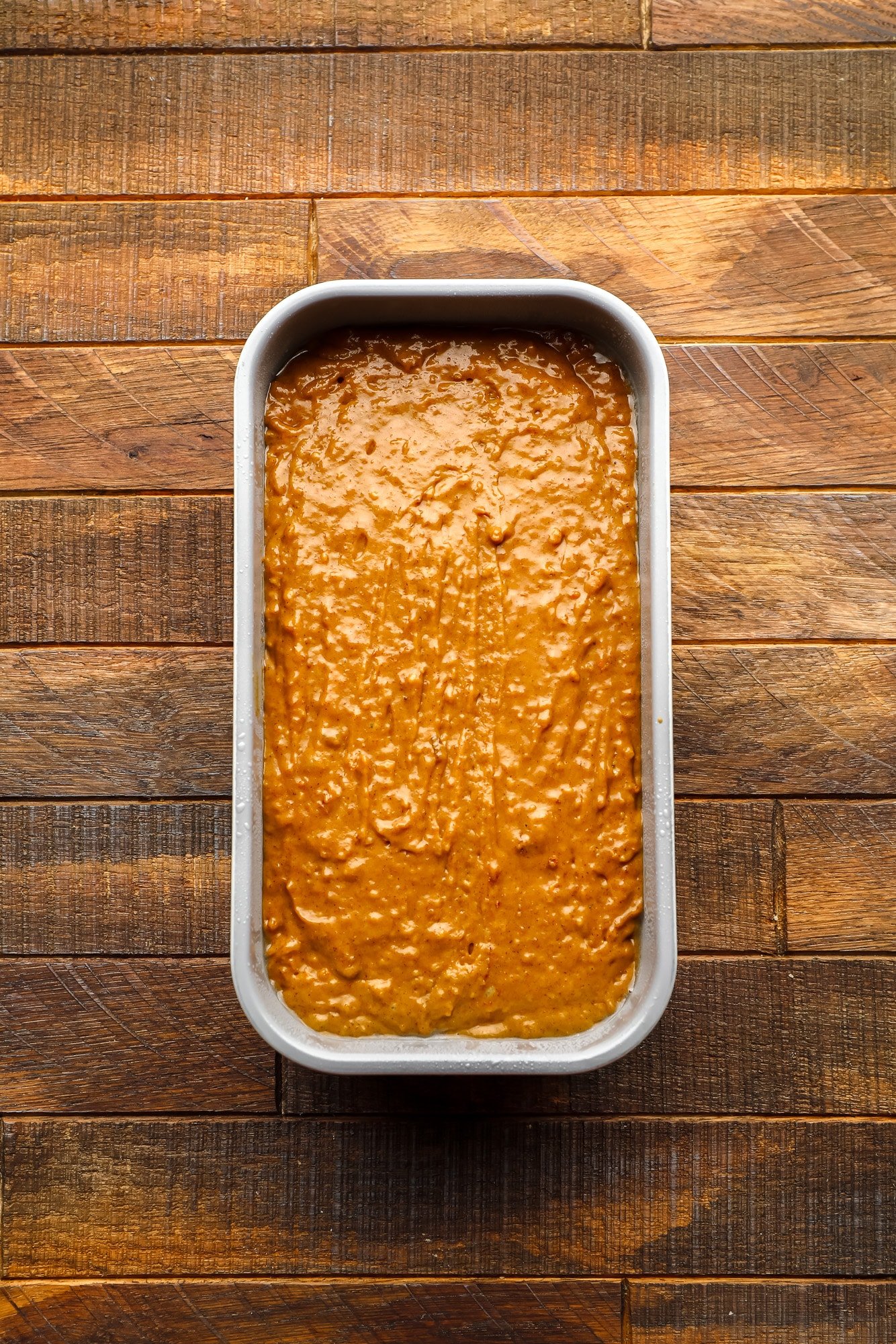 an unbaked gingerbread loaf in a metal loaf pan.