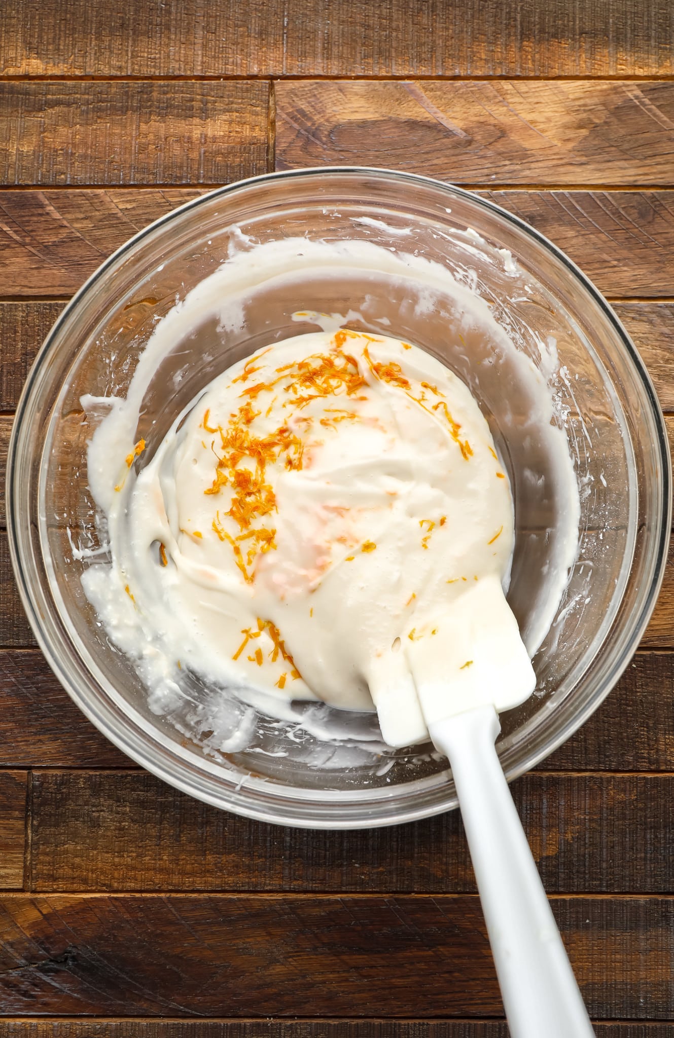 using a spatula to stir orange zest into vegan cream cheese icing.