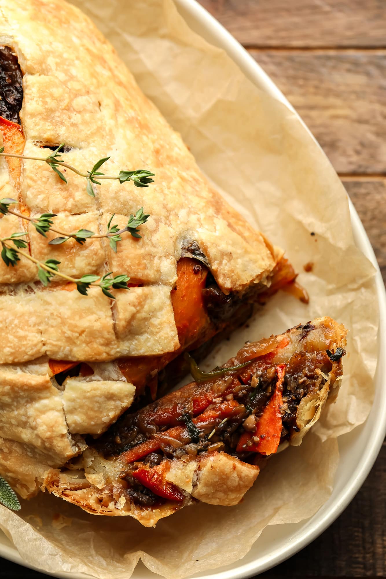 A baked and sliced mushroom wellington topped with fresh thyme.