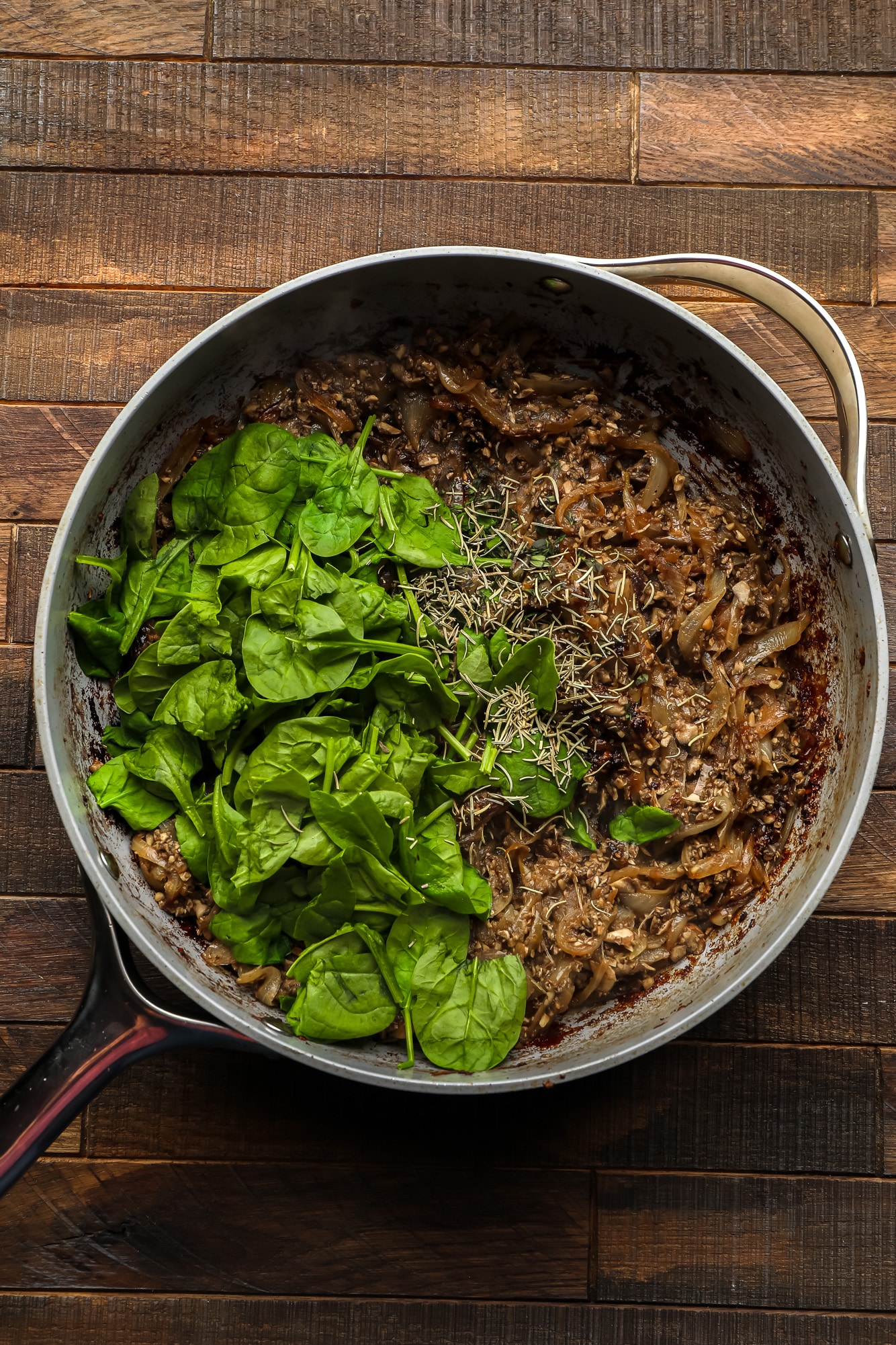 cooking the filling for a mushroom wellington in a large grey skillet.