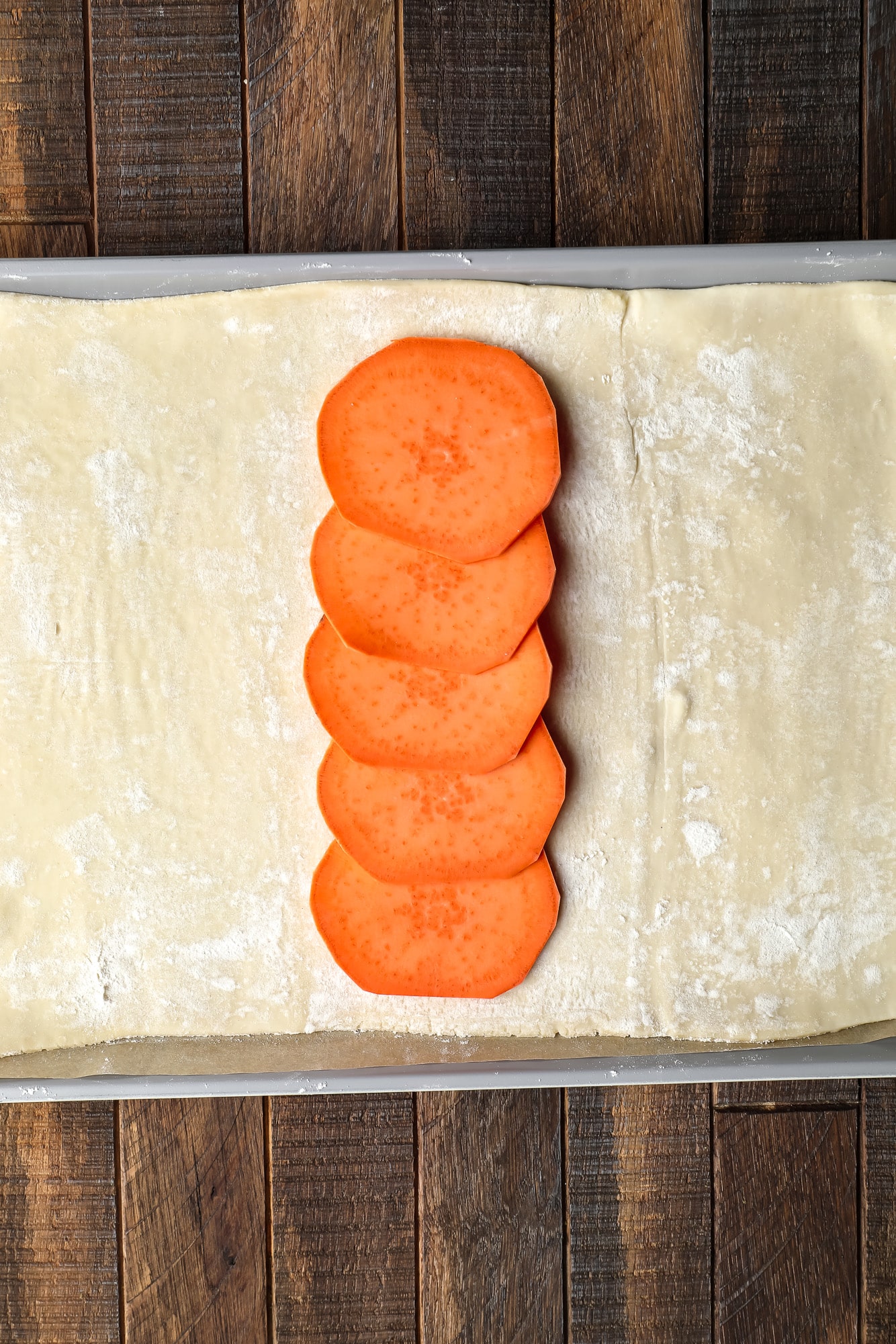 a row of sliced sweet potatoes on a sheet of puff pastry.