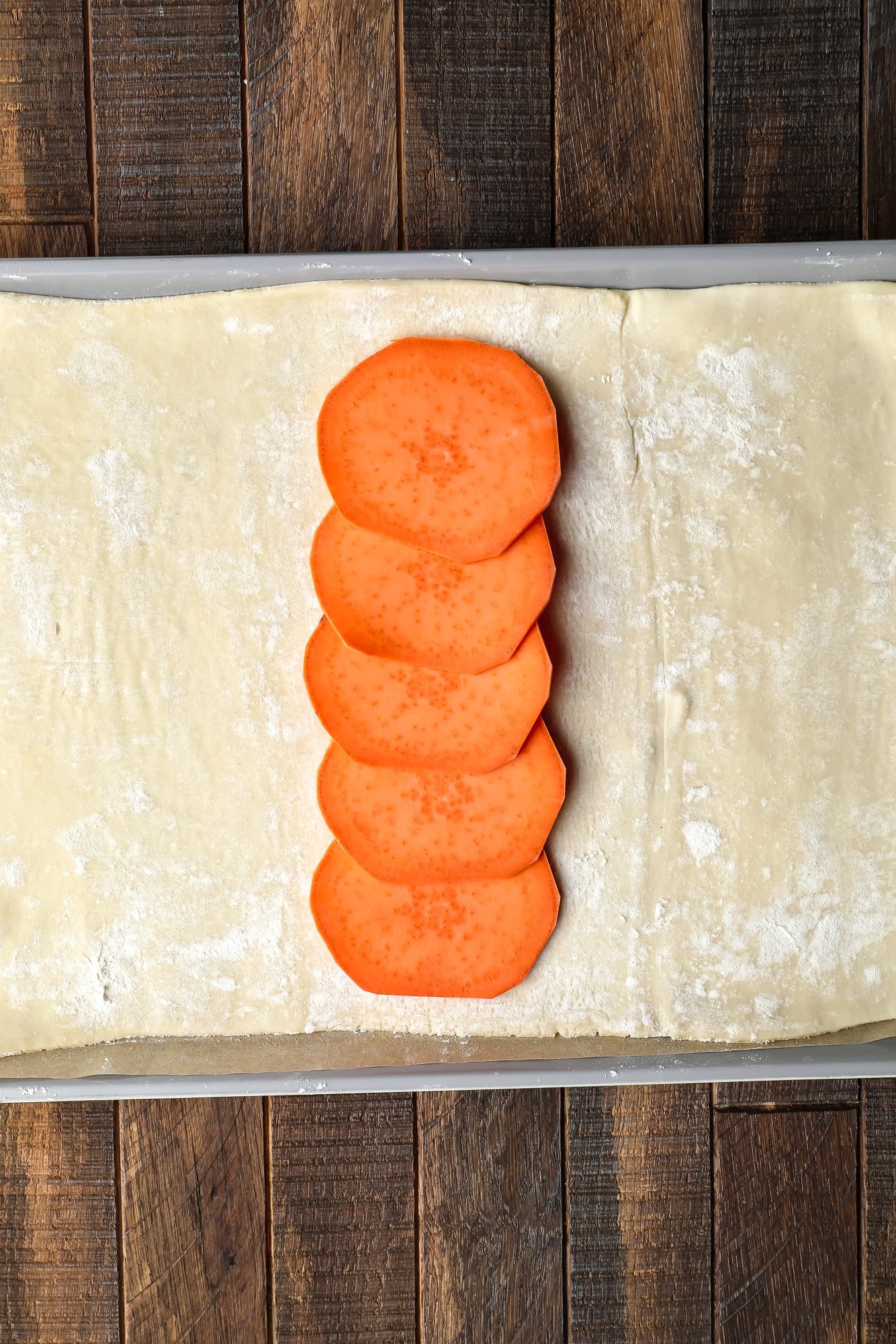 a row of sliced sweet potatoes on a sheet of puff pastry.