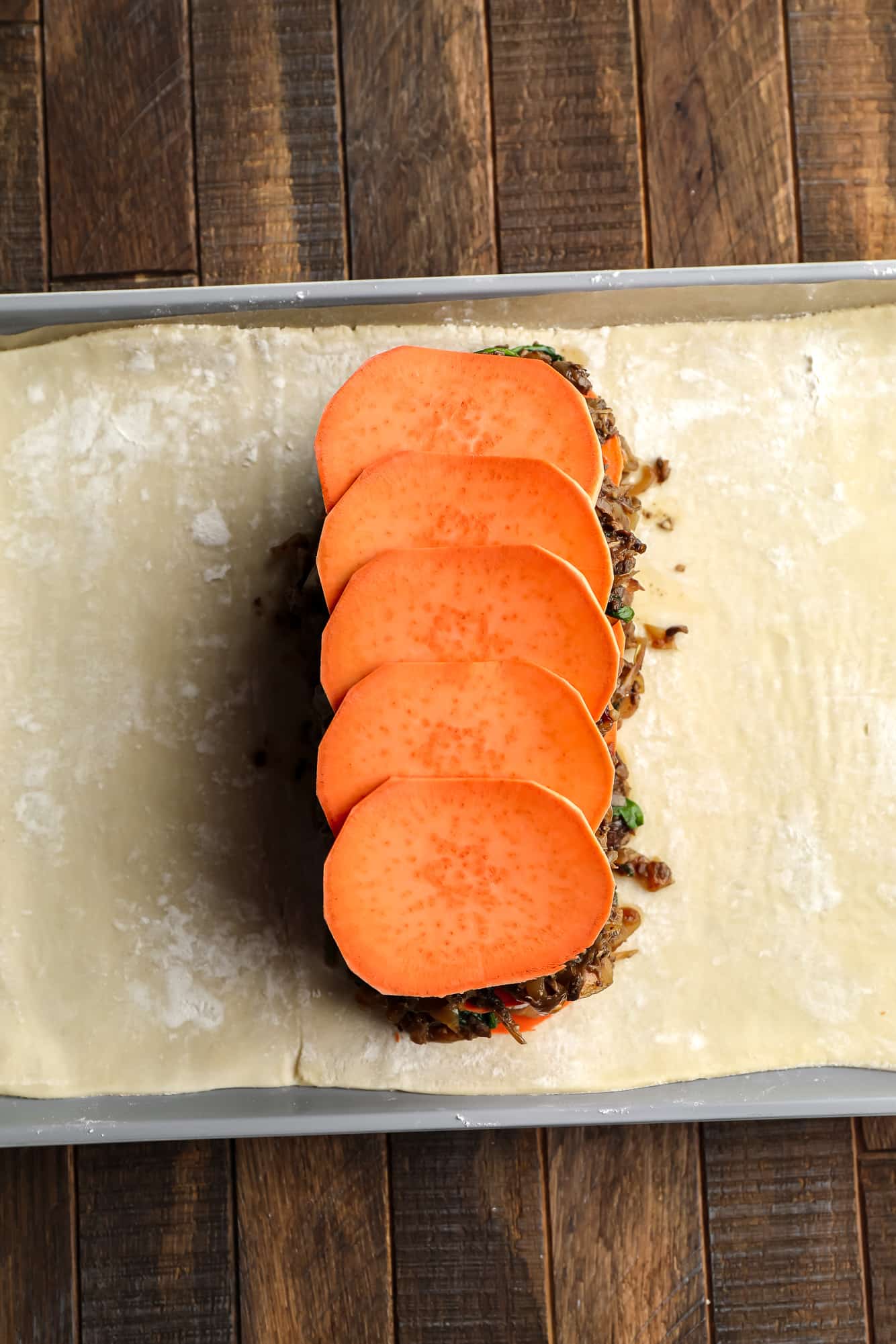 assembling the sweet potato and mushroom filling for mushroom wellington on a sheet of puff pastry.