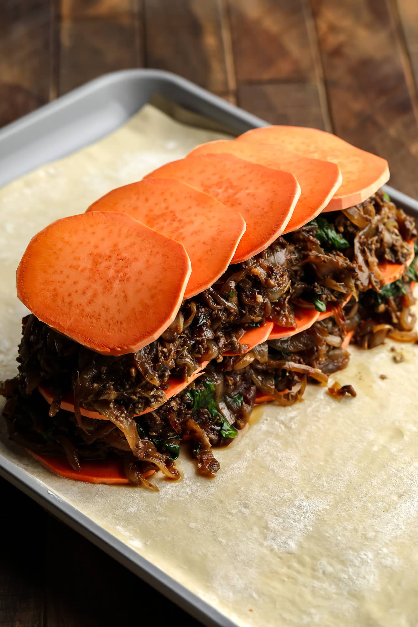 assembling the sweet potato and mushroom filling for mushroom wellington on a sheet of puff pastry.