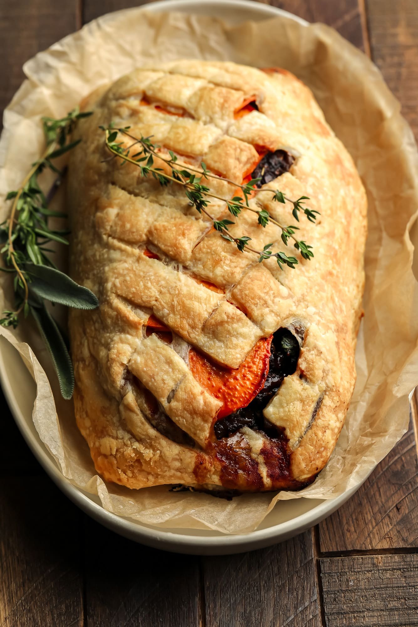A baked and sliced mushroom wellington topped with fresh thyme.