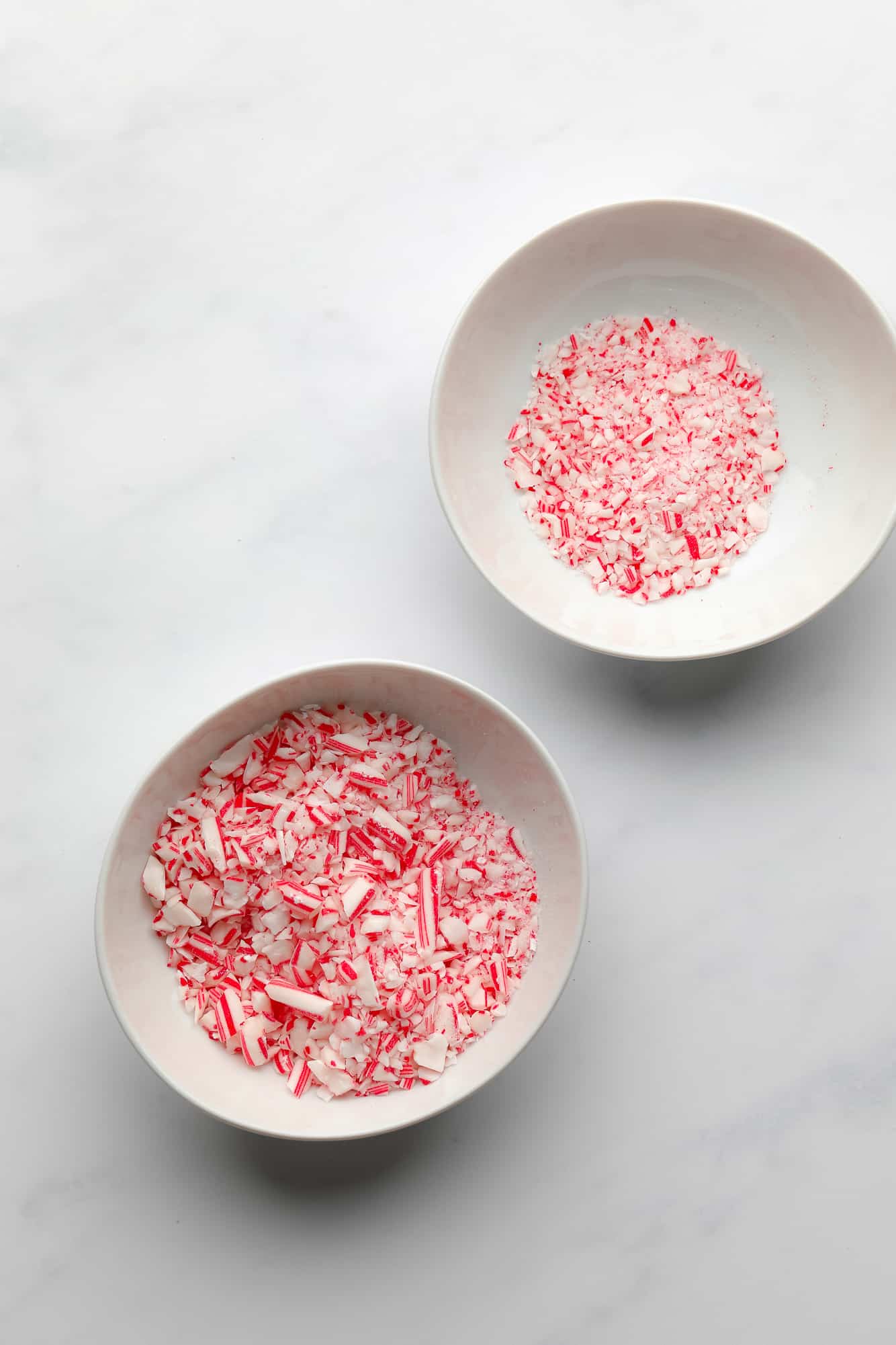 two white bowls filled with candy cane pieces.