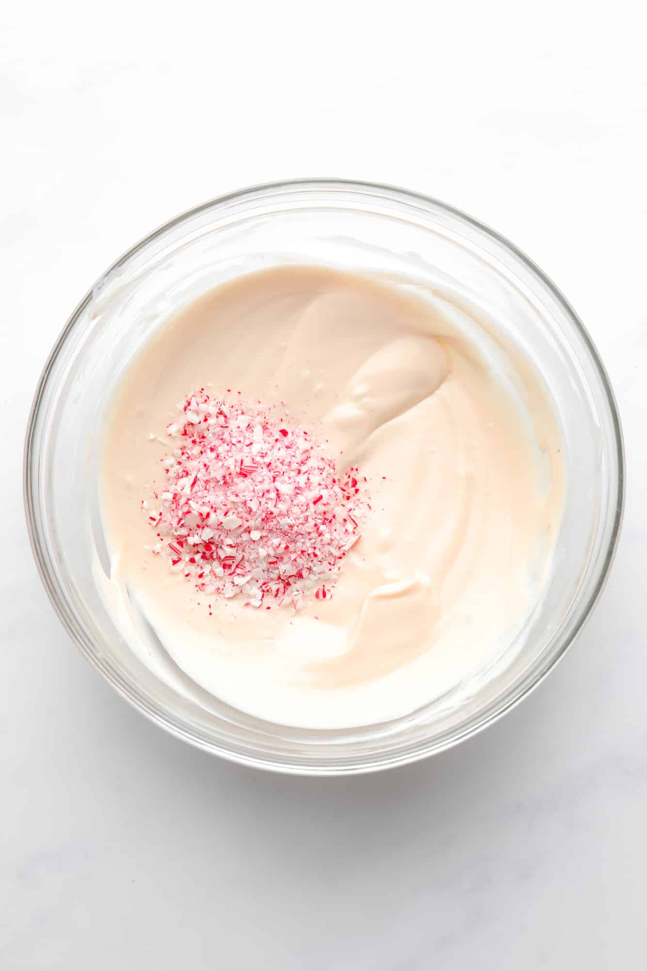 a pile of crushed candy canes in a bowl of melted vegan white chocolate.