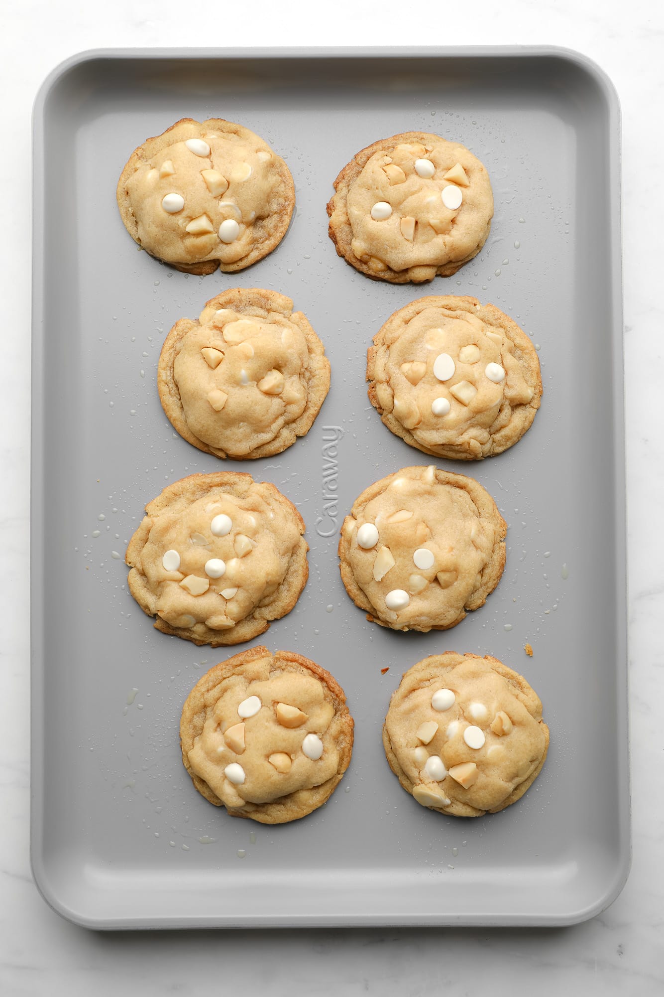 baked Vegan White Chocolate Macadamia Nut Cookies on a metal baking sheet.