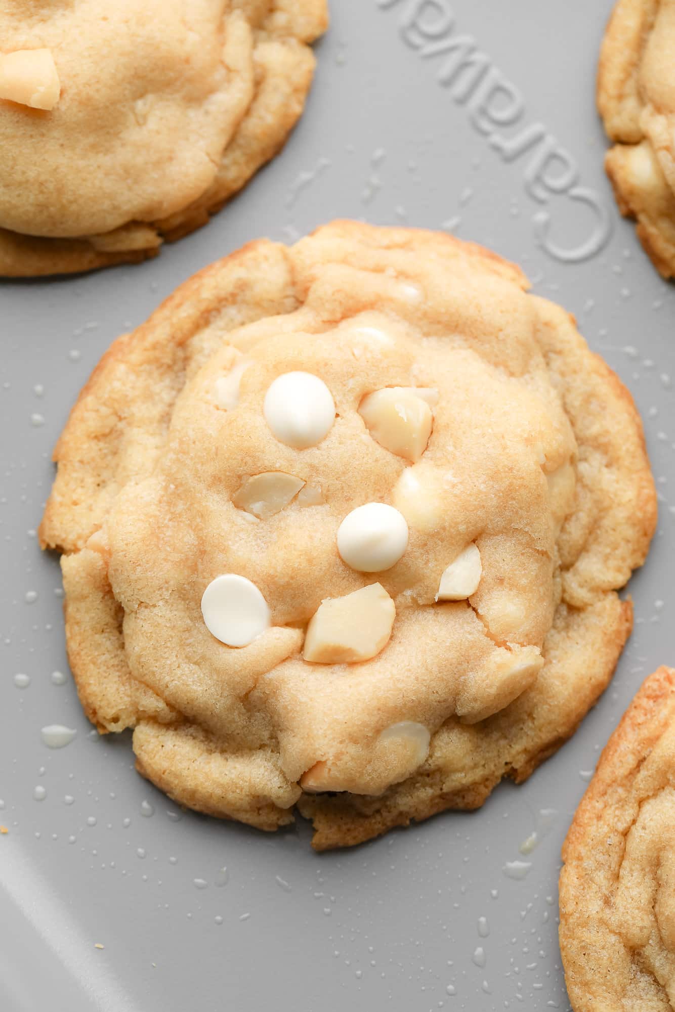 close up of a Vegan White Chocolate Macadamia Nut Cookie on a baking sheet.