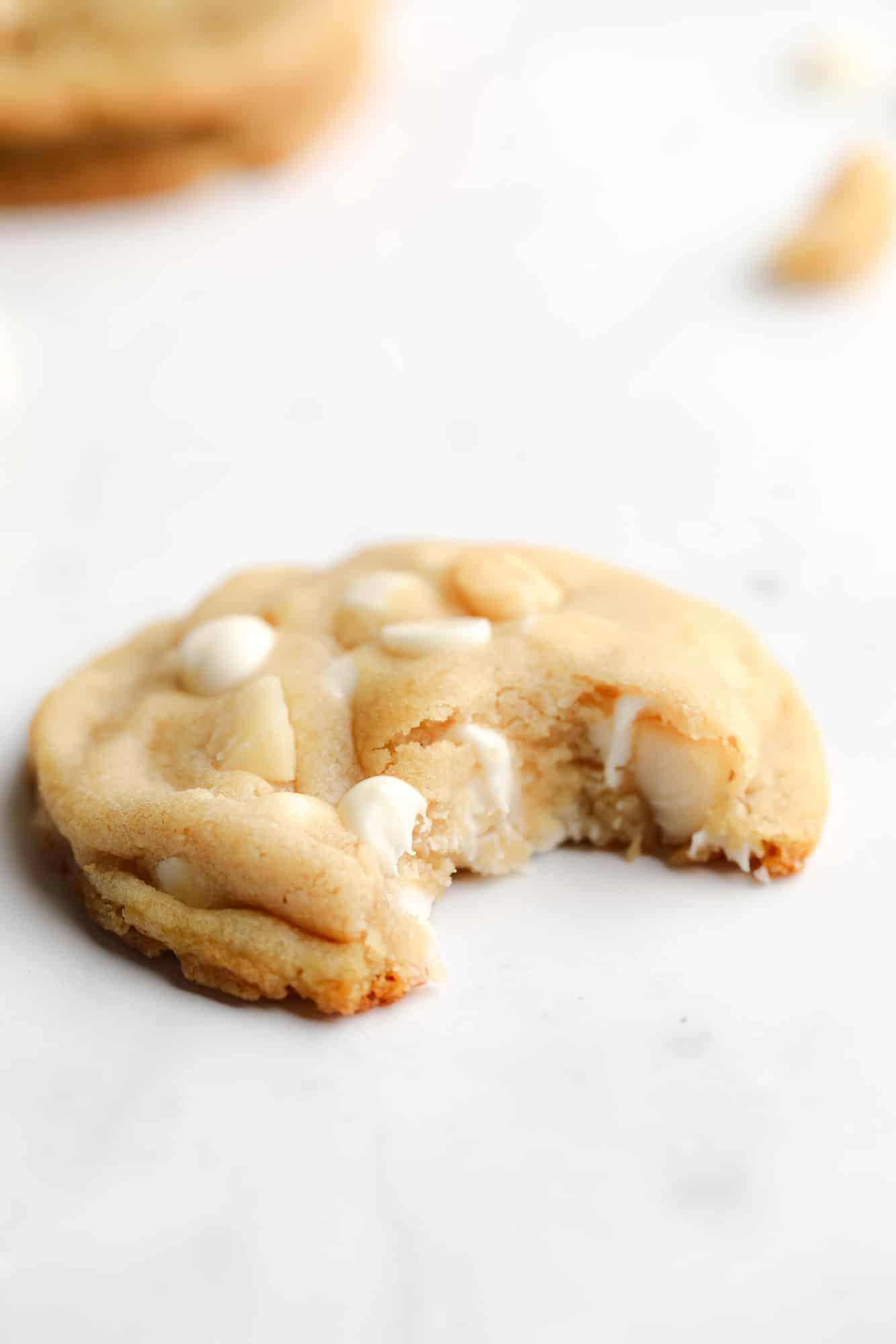 close up on a Vegan White Chocolate Macadamia Nut Cookie with a bite taken out of it.