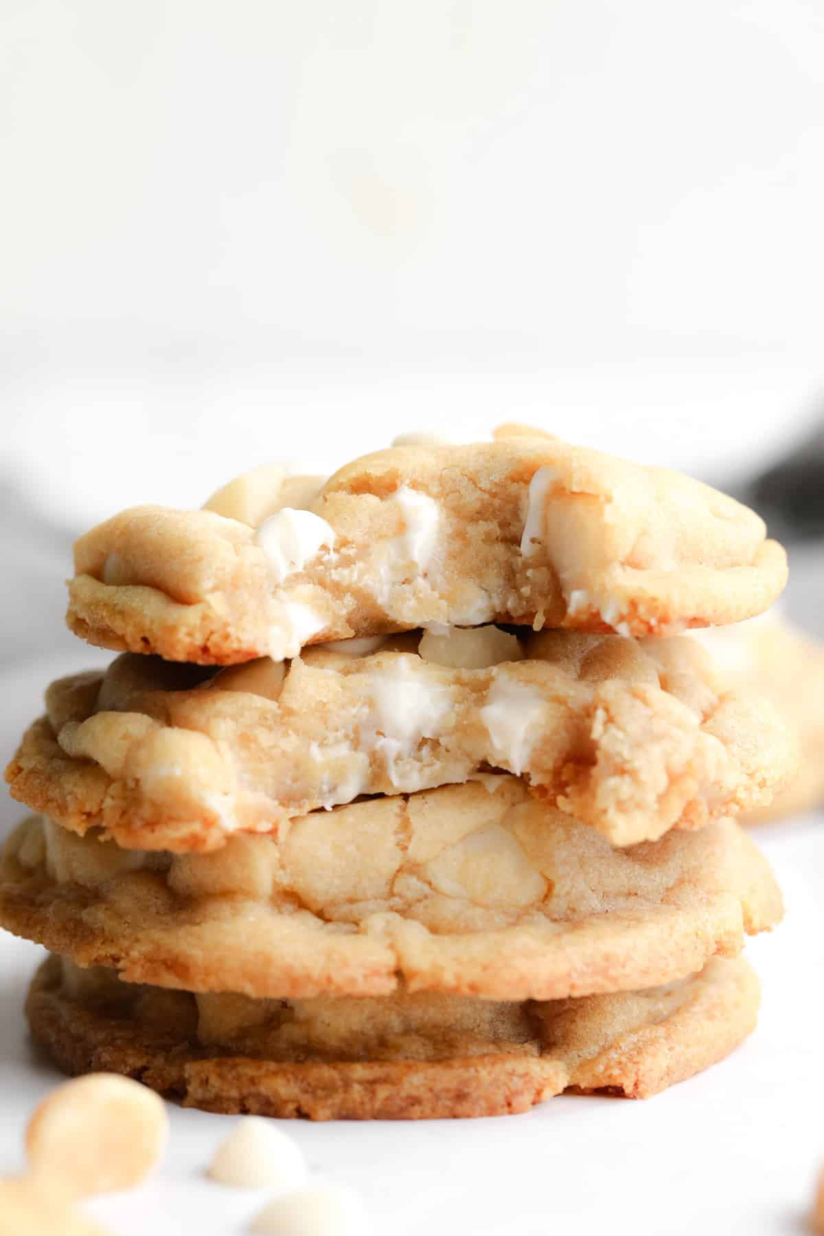a stack of Vegan White Chocolate Macadamia Nut Cookies with bites taken out of them.