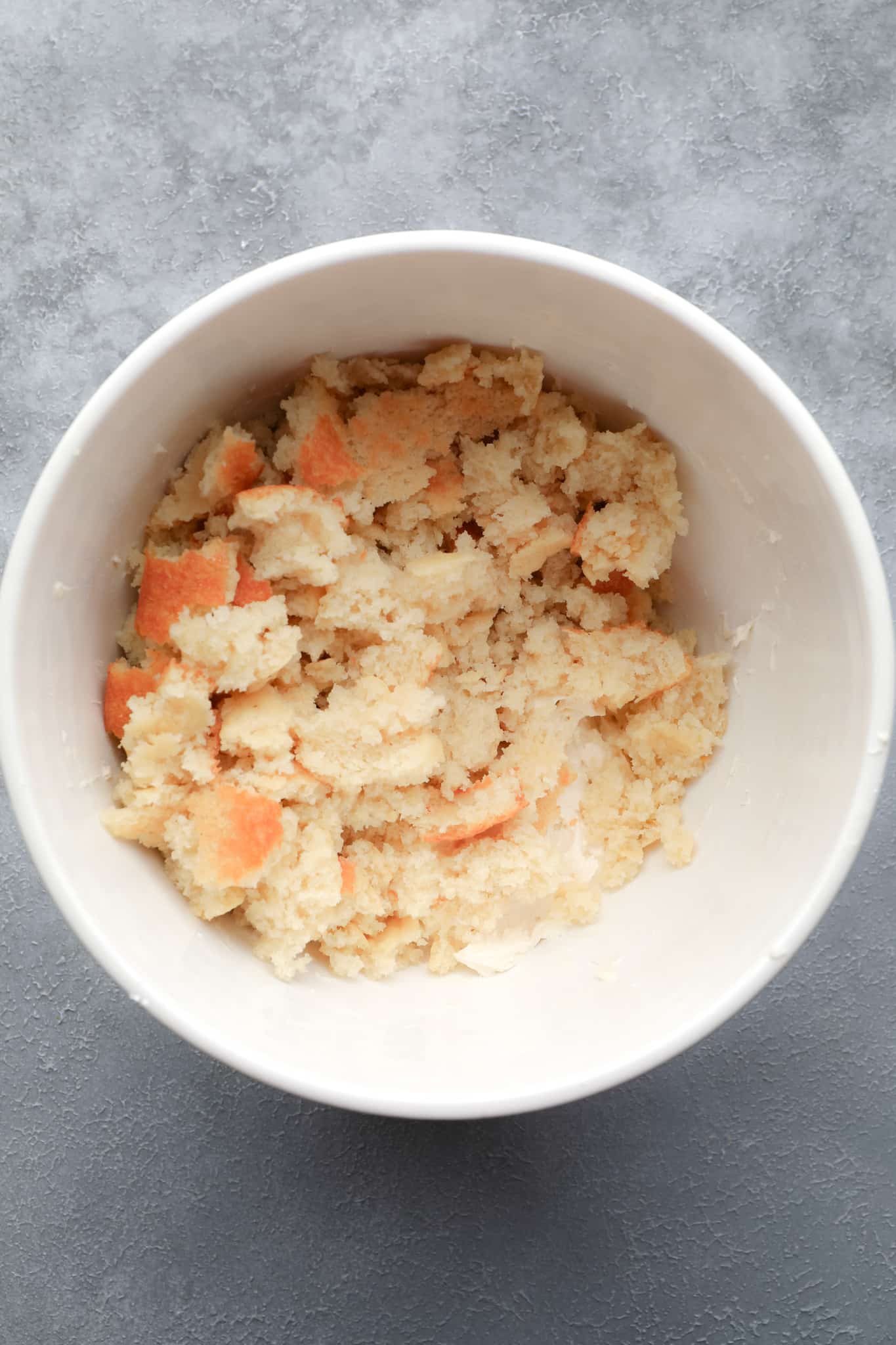 crumbled vegan vanilla cake in a large white bowl.