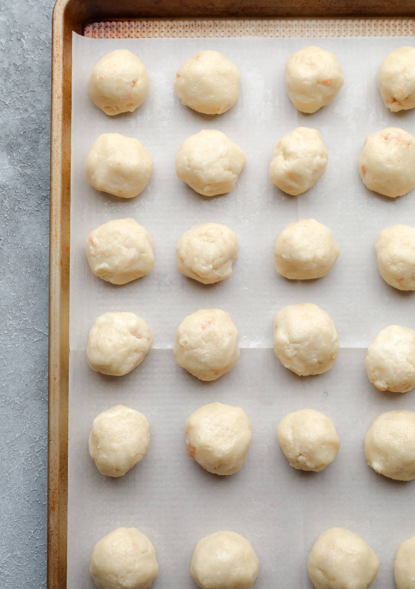 rows of rolled vanilla cake balls on a parchment-lined baking sheet.