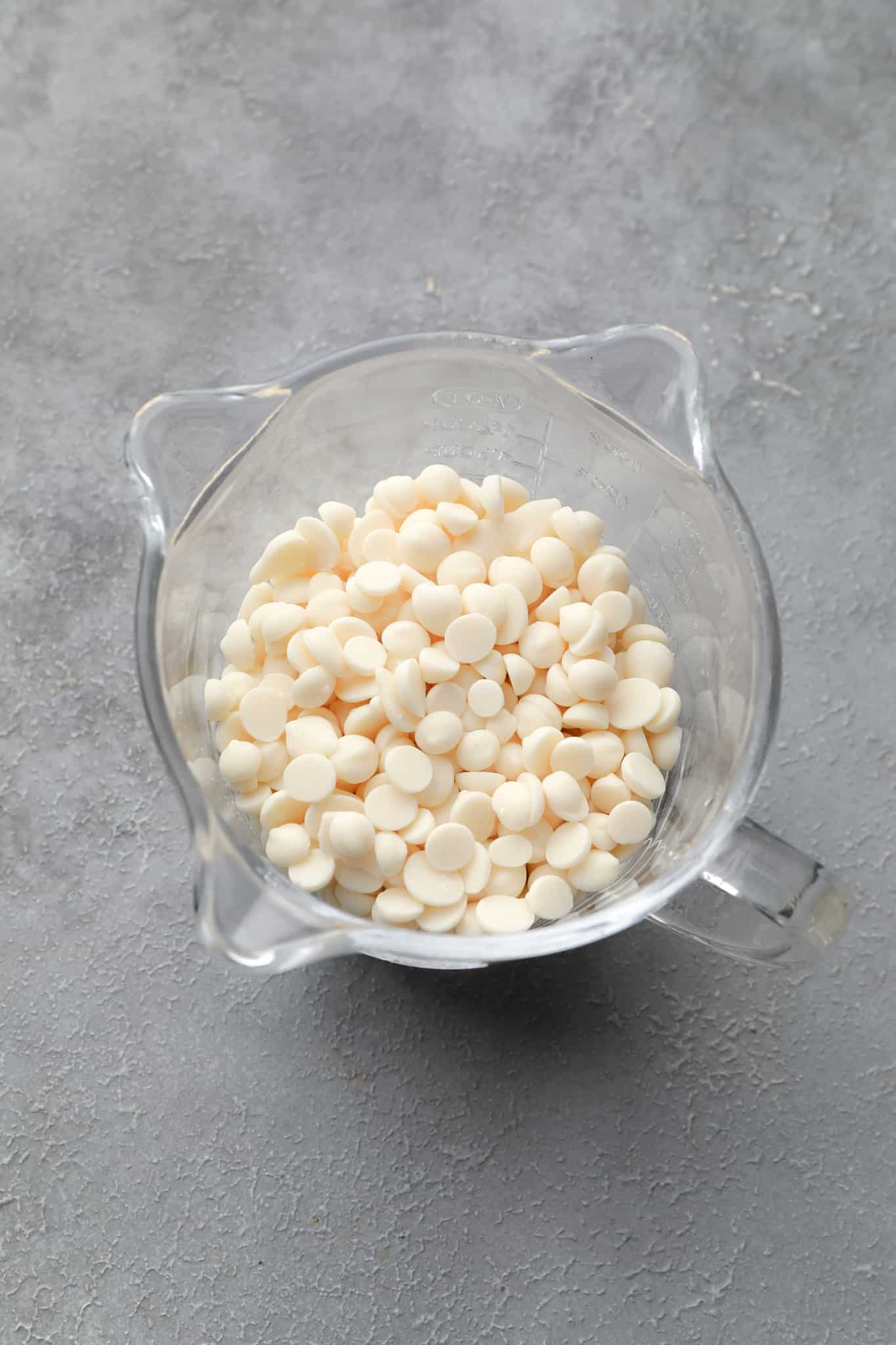 vegan white chocolate chips in a glass measuring cup.