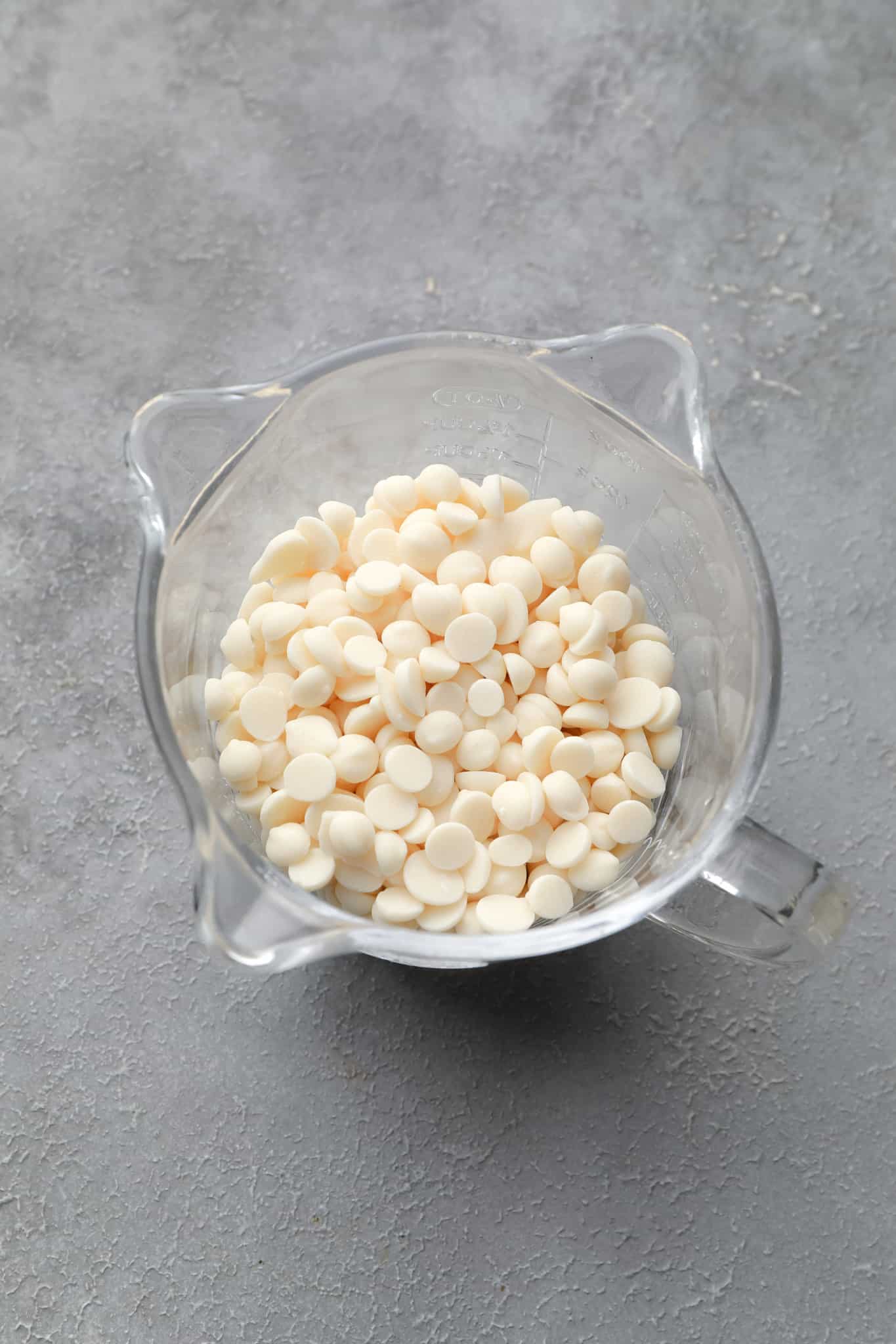 vegan white chocolate chips in a glass measuring cup.