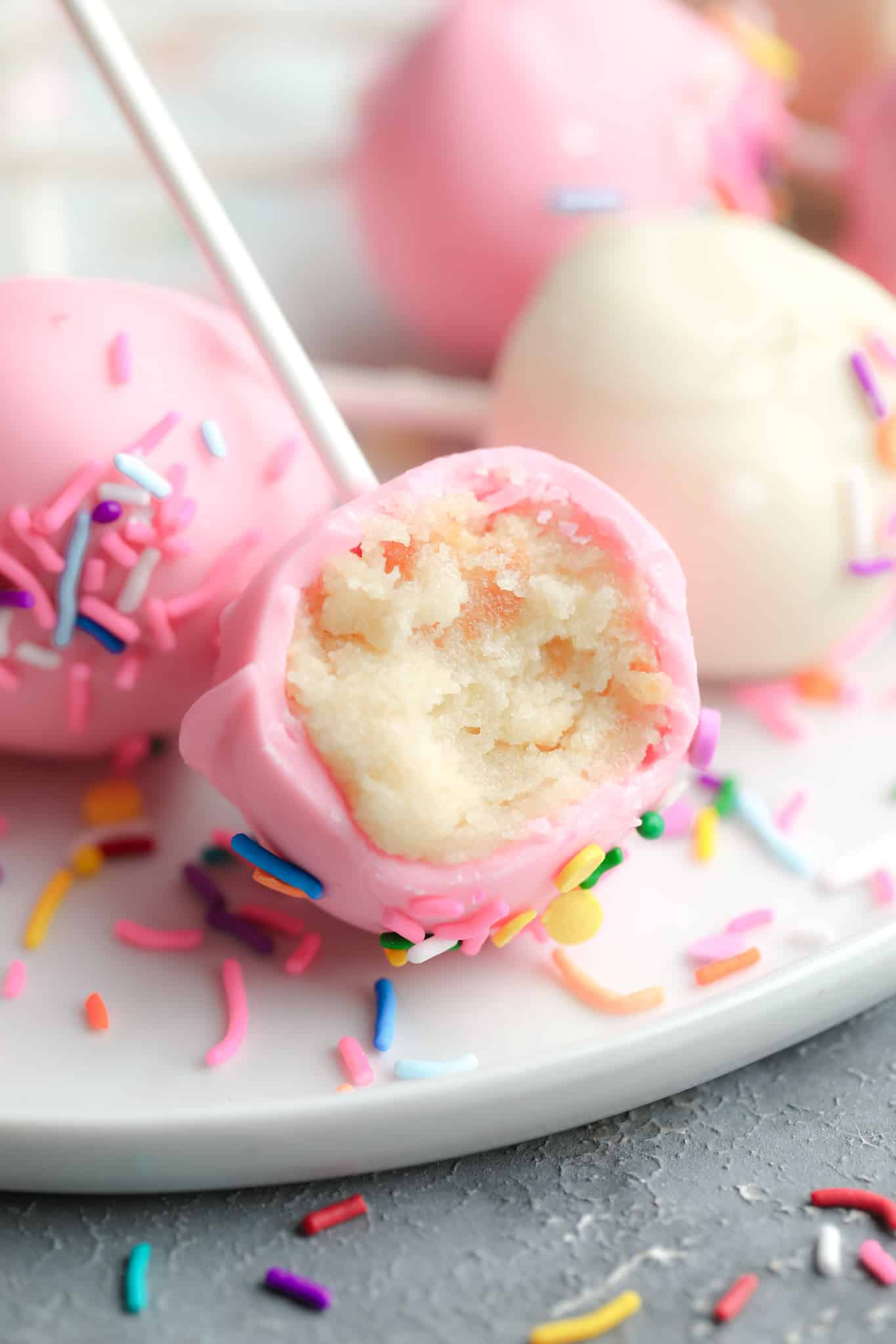 close up of a pink vanilla vegan cake pop with a bite taken out of it.