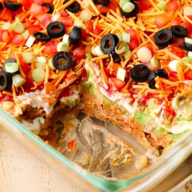 close up on a vegan 7 layer dip in a glass dish.