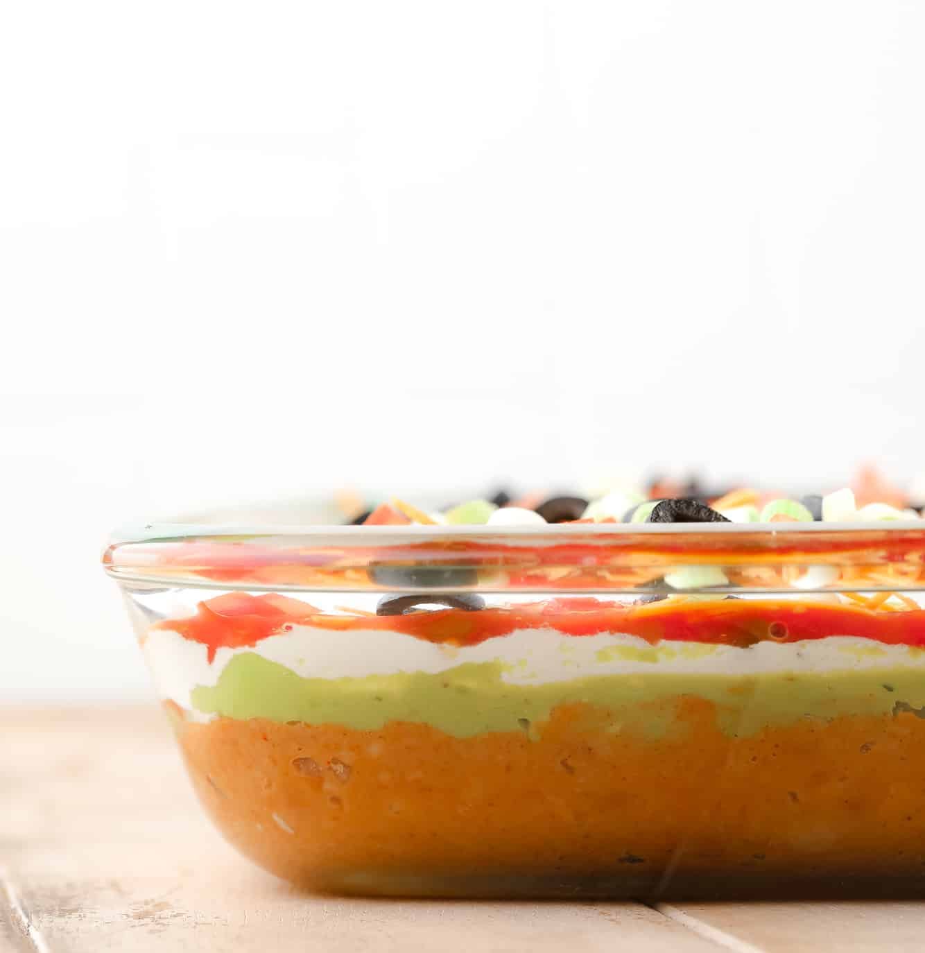 side view of vegan 7 layer dip in a glass dish.